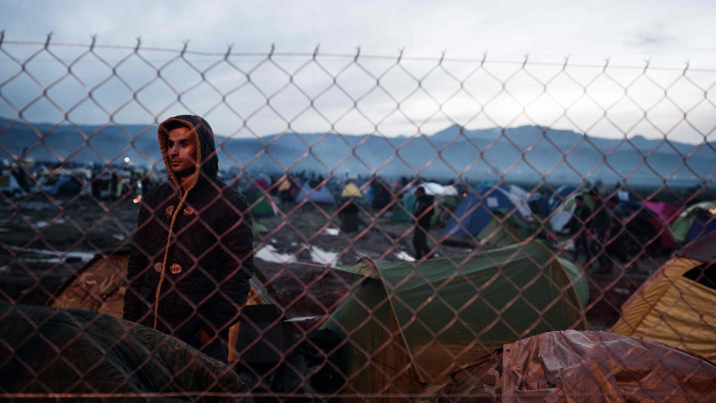 Ein Flüchtling steht hinter einem Zaun im Flüchtlingslager Idomeni 