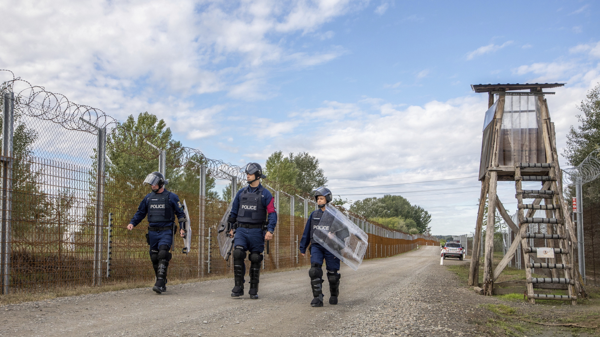 Polizisten mit schwerer Schutzausrüstung gehen auf der ungarischen Seite der Grenze nach Serbien entlang. | dpa