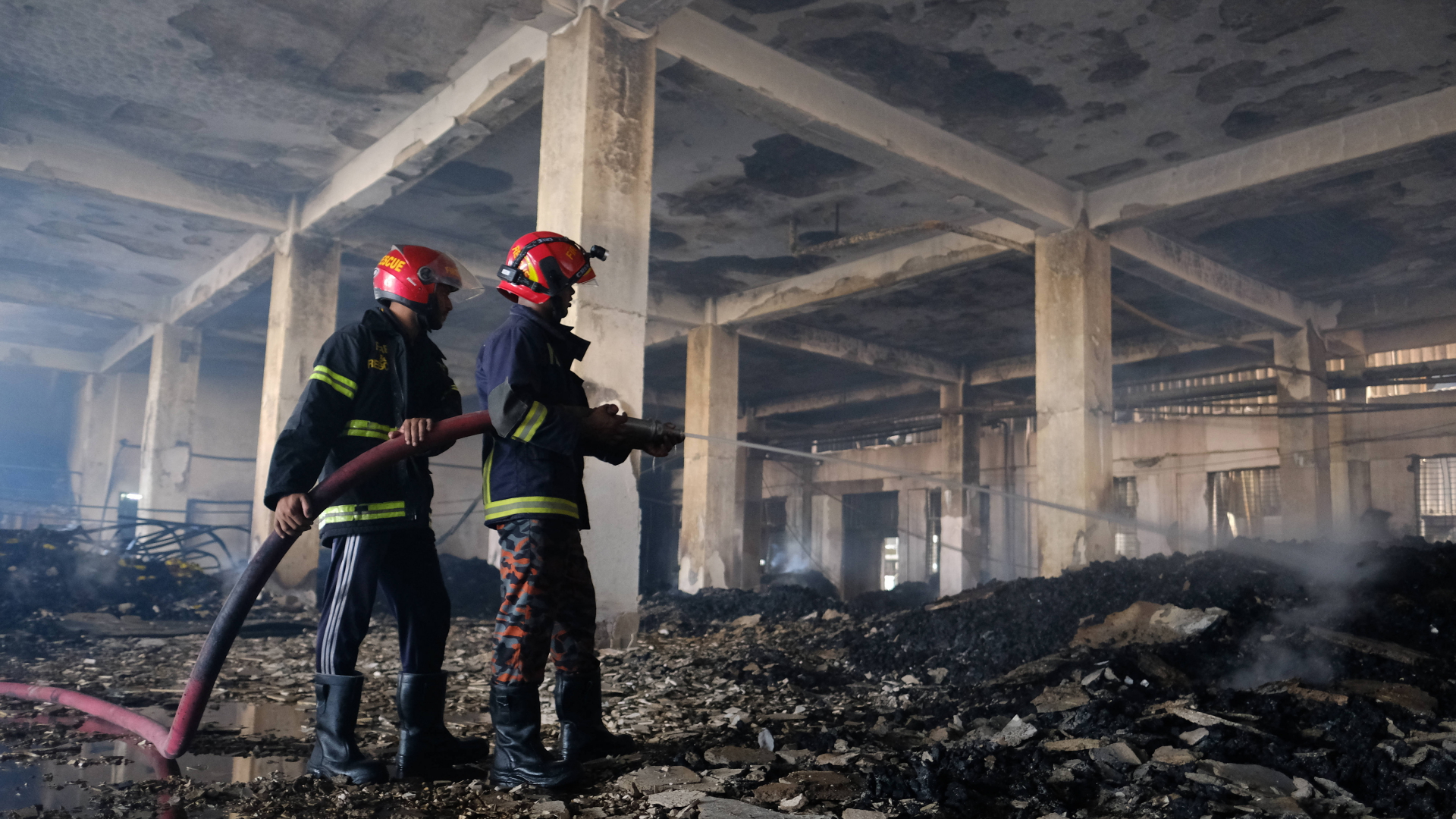 Feuerwehrleute löschen in einer ausgebrannten Fabrik in Bangladesch letzte Glutnester in den verkohlten Trümmern. | dpa