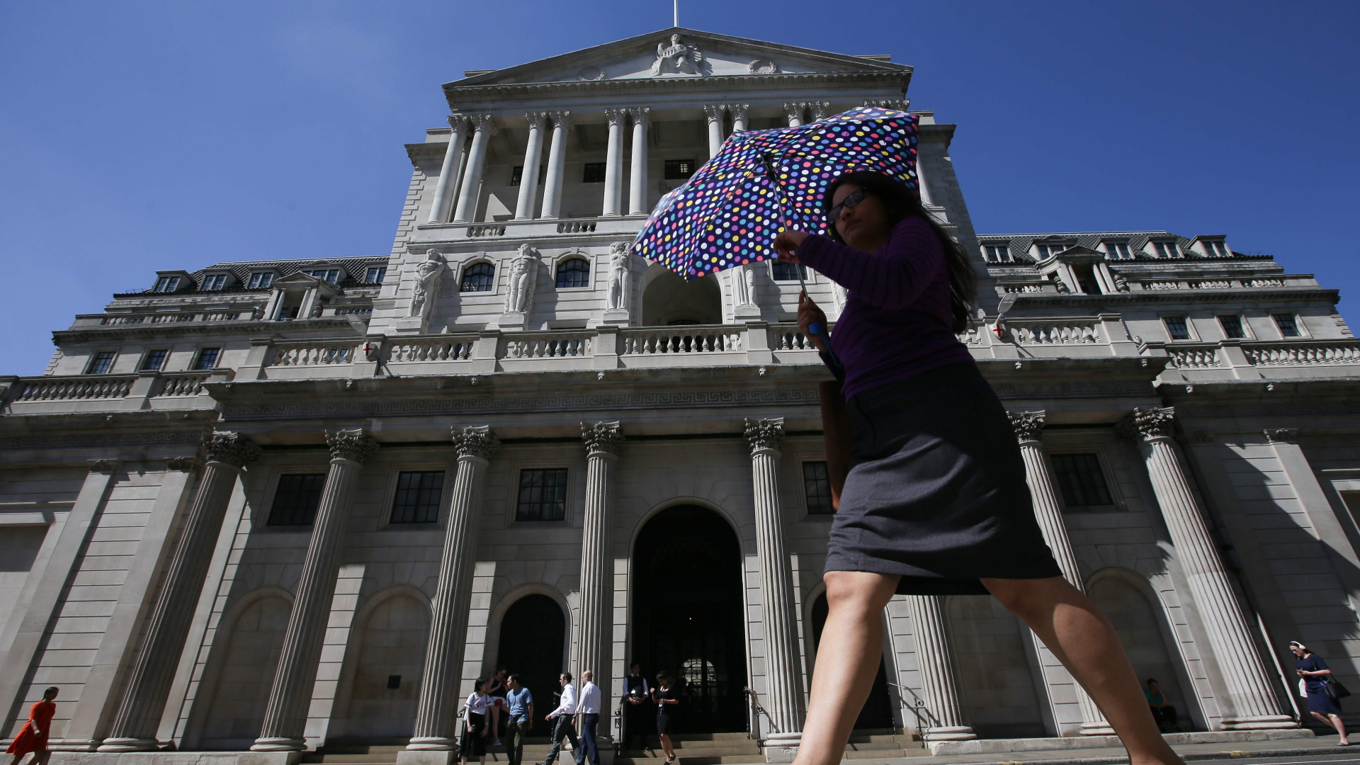 Eine Frau geht mit einem Schirm an der Bank of England vorbei | AFP