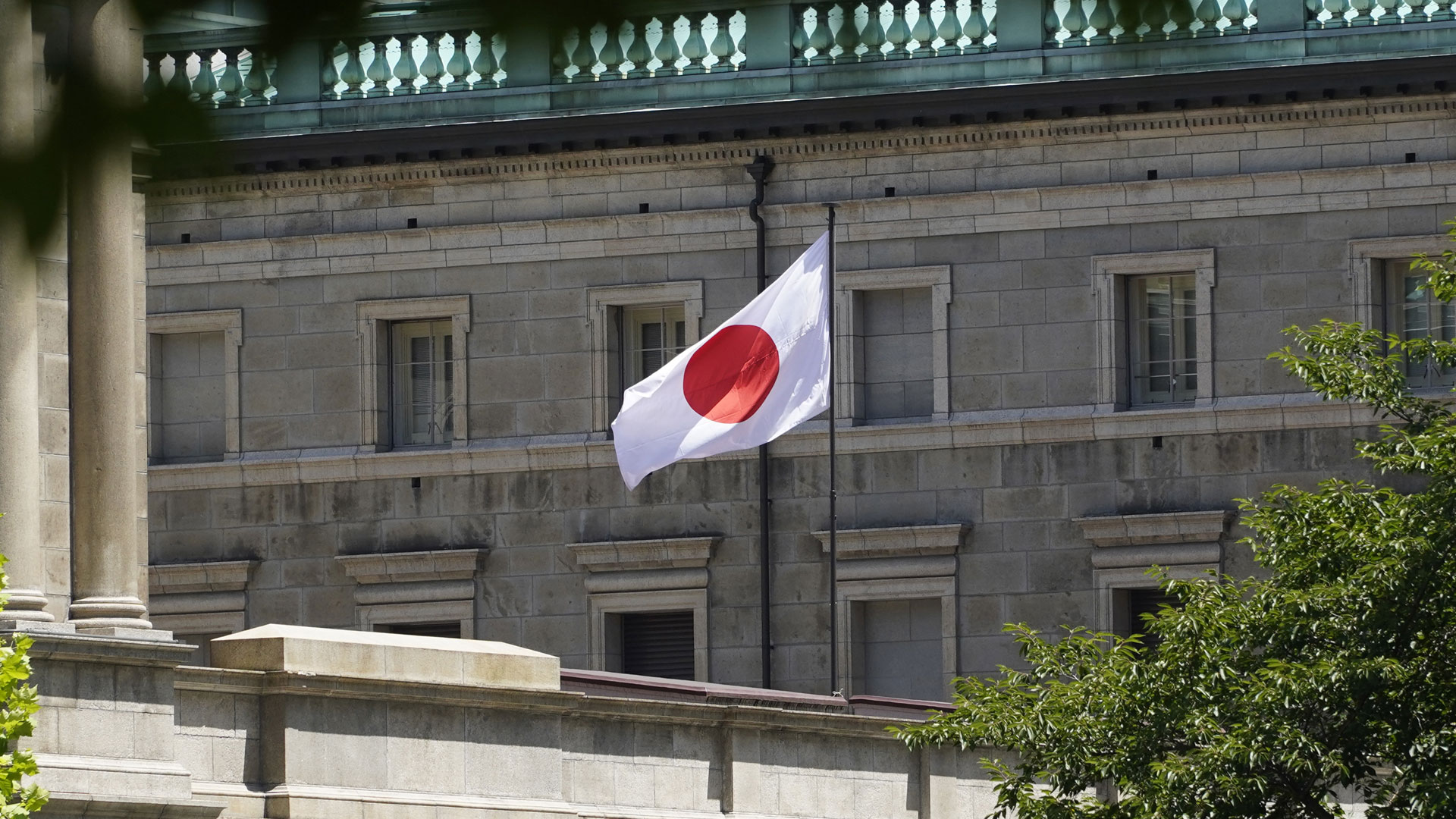 Die japanische Nationalflagge flattert am Hauptsitz der Bank of Japan in Tokio.  | picture alliance/dpa/Jiji Press 