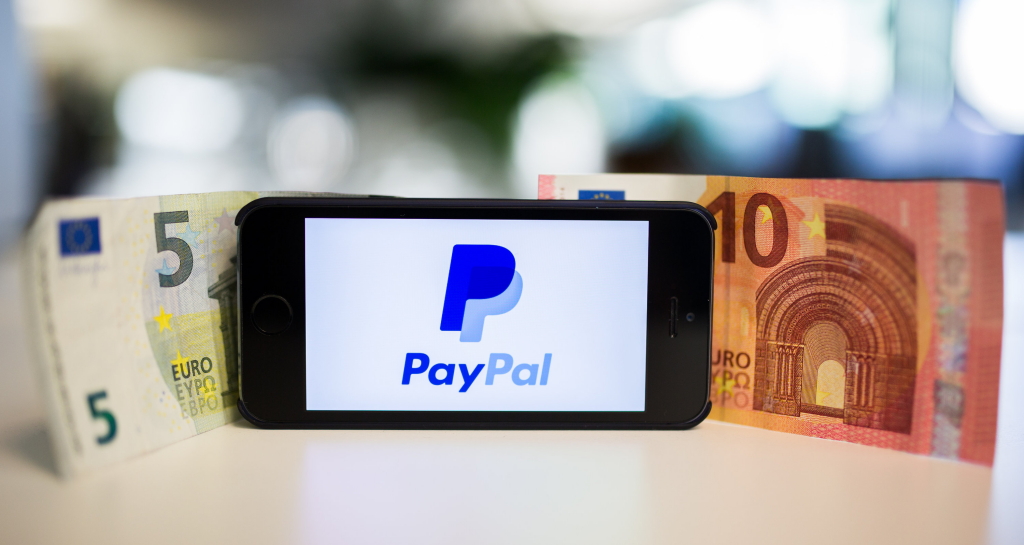 Banknoten und Smartphone mit PayPal-Logo