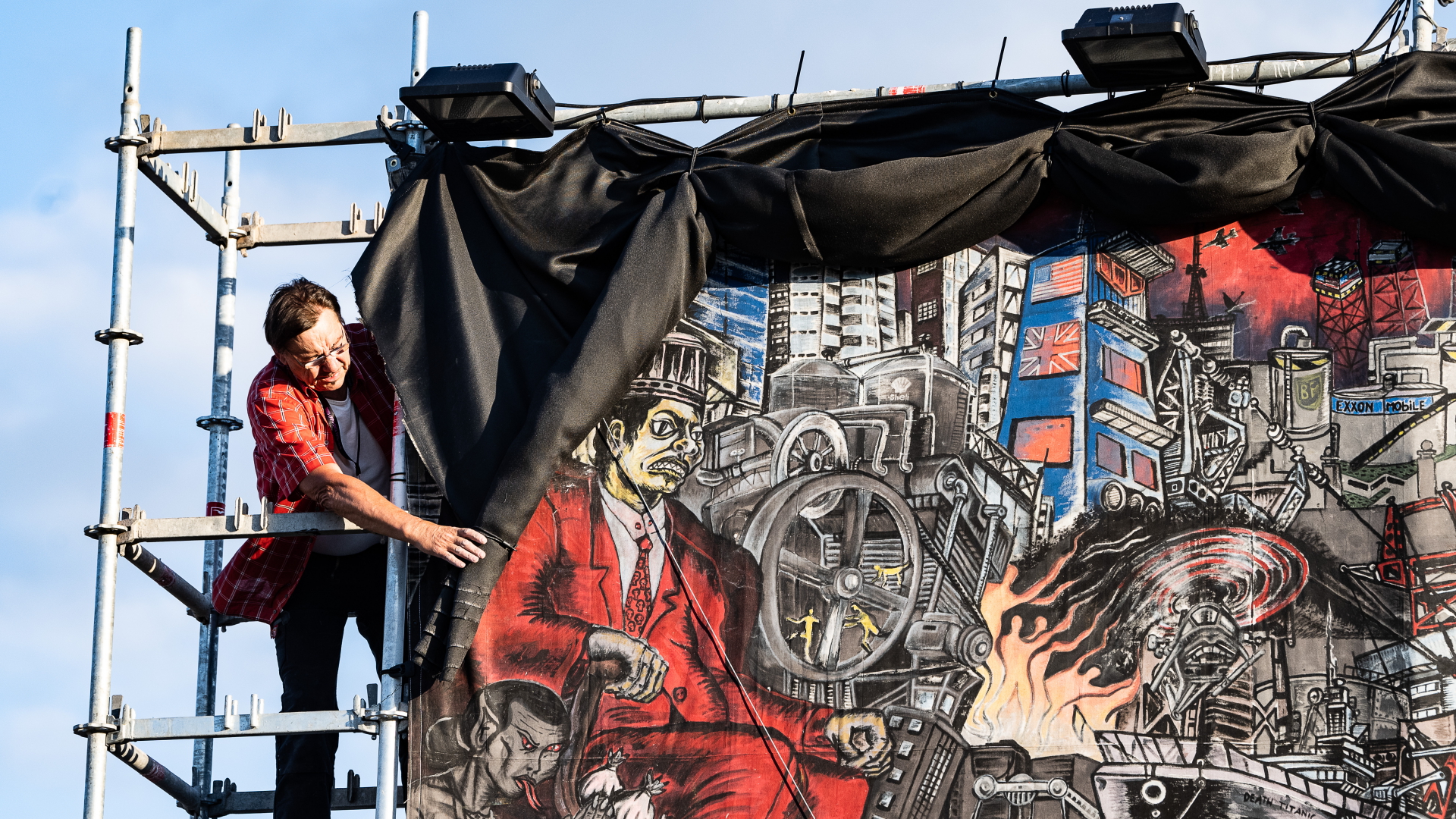 Ein Mitarbeiter der documenta fifteen verhüllt ein großflächiges Banner des Kollektivs Taring Padi.  | dpa
