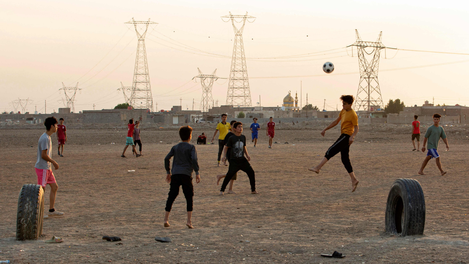 Junge Männer und Jugendliche spielen Fußball auf einem Feld in Basra. | AFP