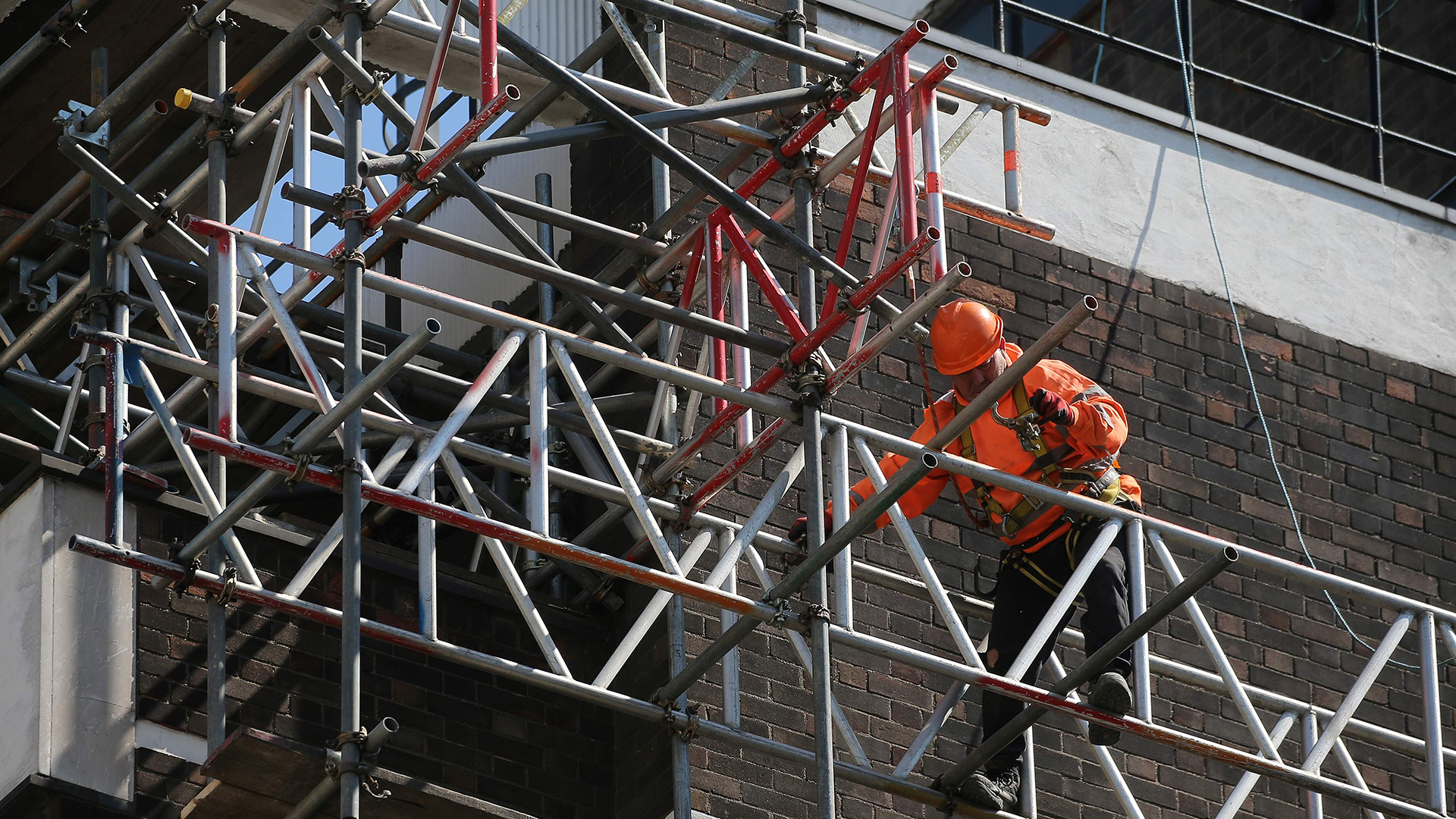 Ein Arbeiter klettert auf einem Gerüst auf einer Baustelle in London | AFP