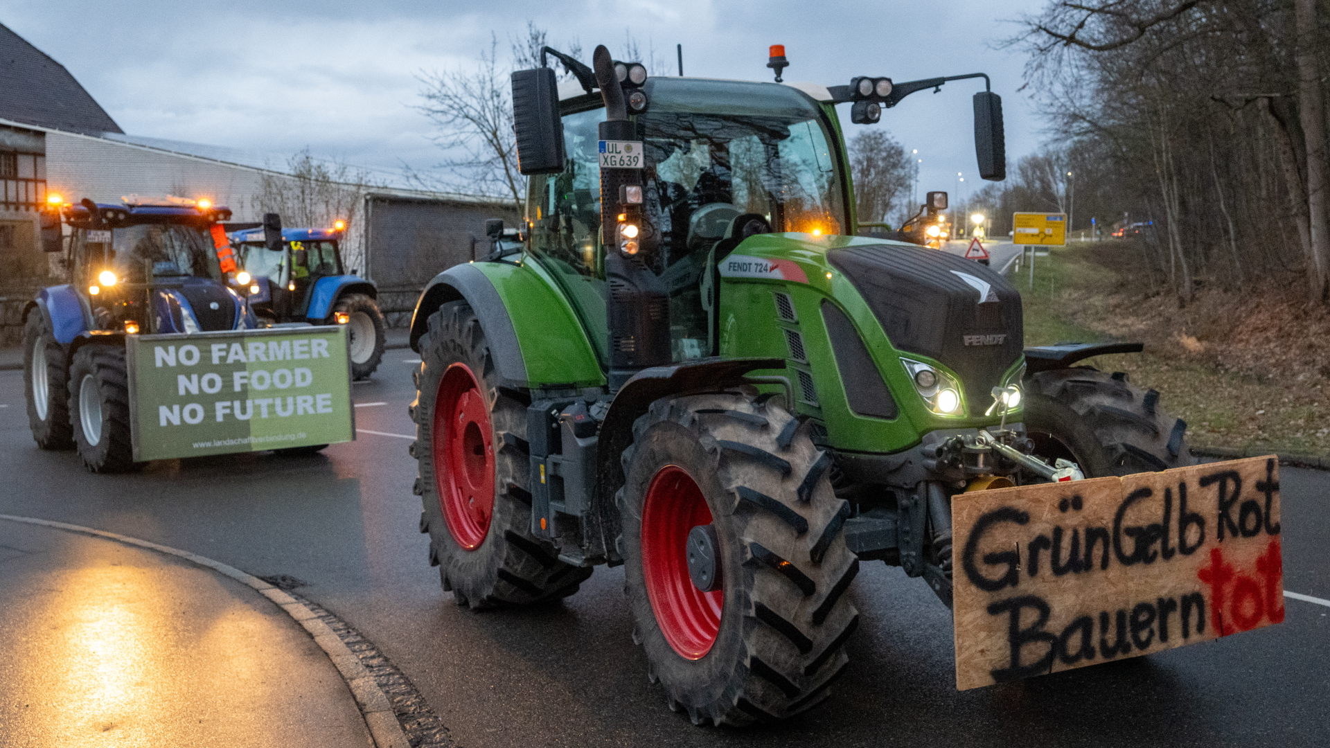 Nach einer Kundgebung des Bauernverbandes gegen die Sparpläne der Bundesregierung fahren Landwirte im Konvoi durch die Stadt Günzburg, auf einem Plakat steht "GrünGelbRot Bauern tot". 