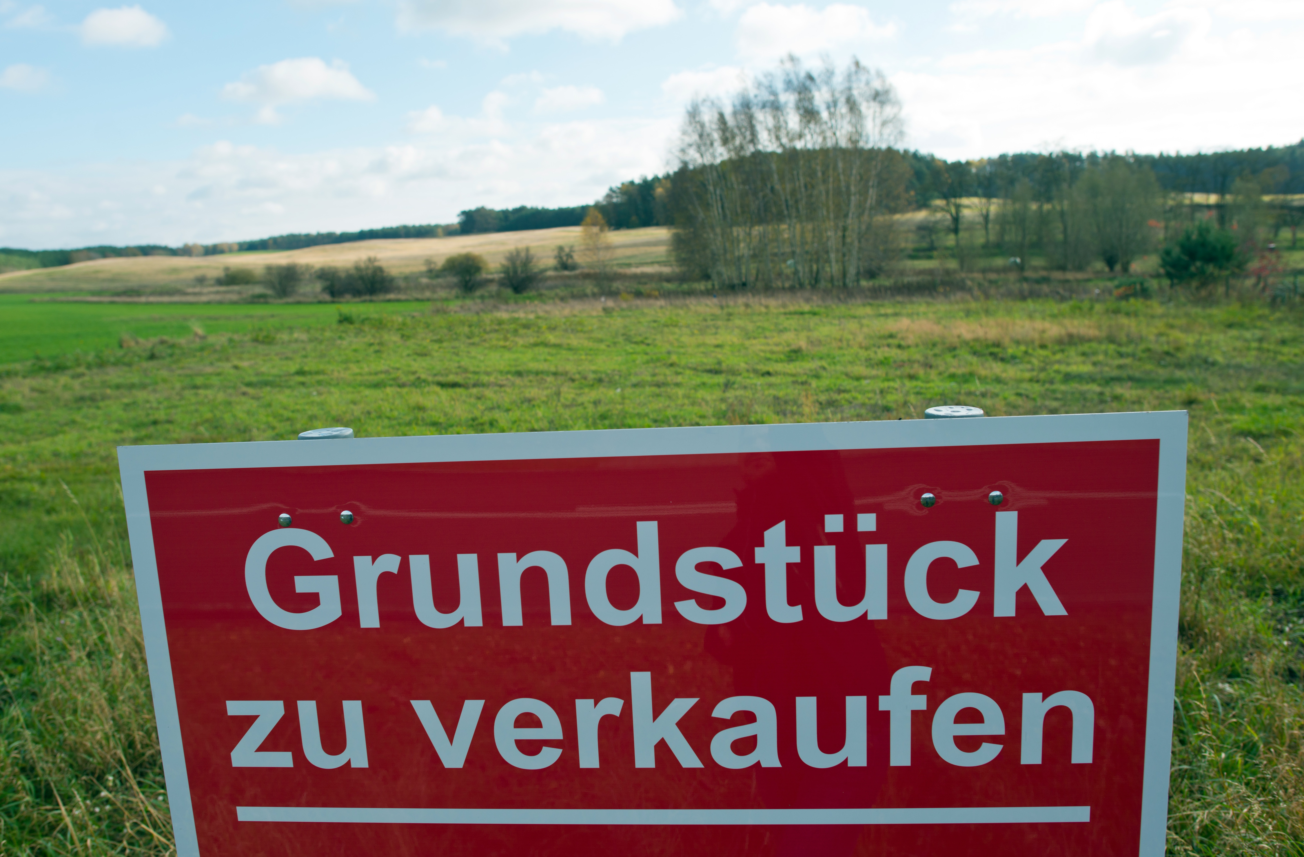 Schild mit der Aufschrift "Grundstück zu verkaufen" steht an einer Wiese | dpa