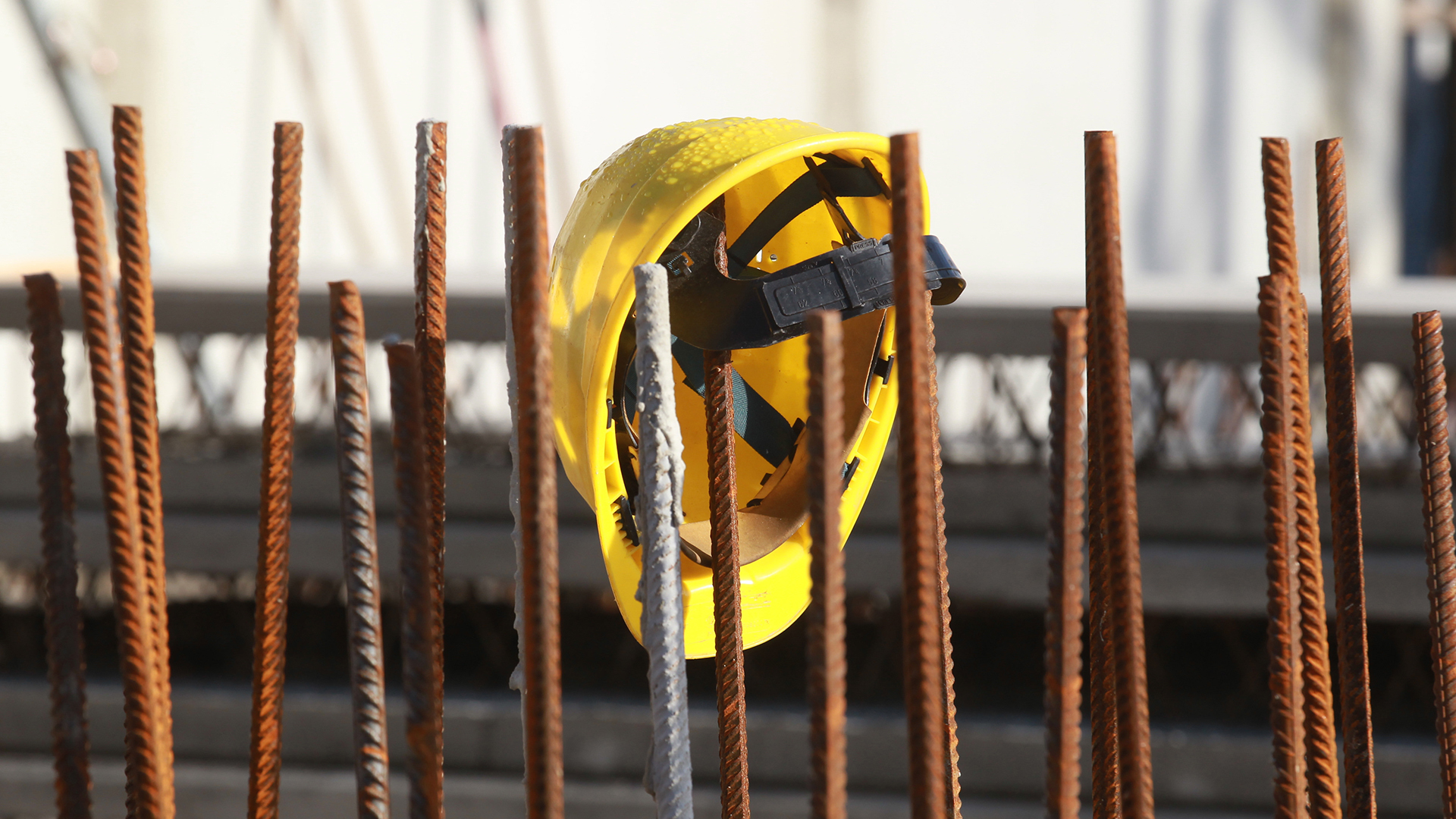 Ein Bauhelm hängt an Fundament-Stangen auf einer Baustelle. | picture alliance/dpa/dpa-Zentral