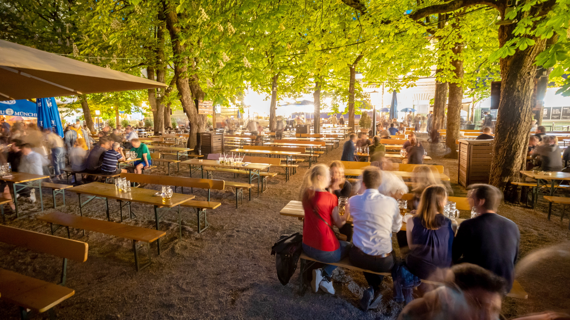 Die letzten Besucher eines Biergartens am Wiener Platz sitzen kurz vor der Schließung des noch an Biertischen. | dpa