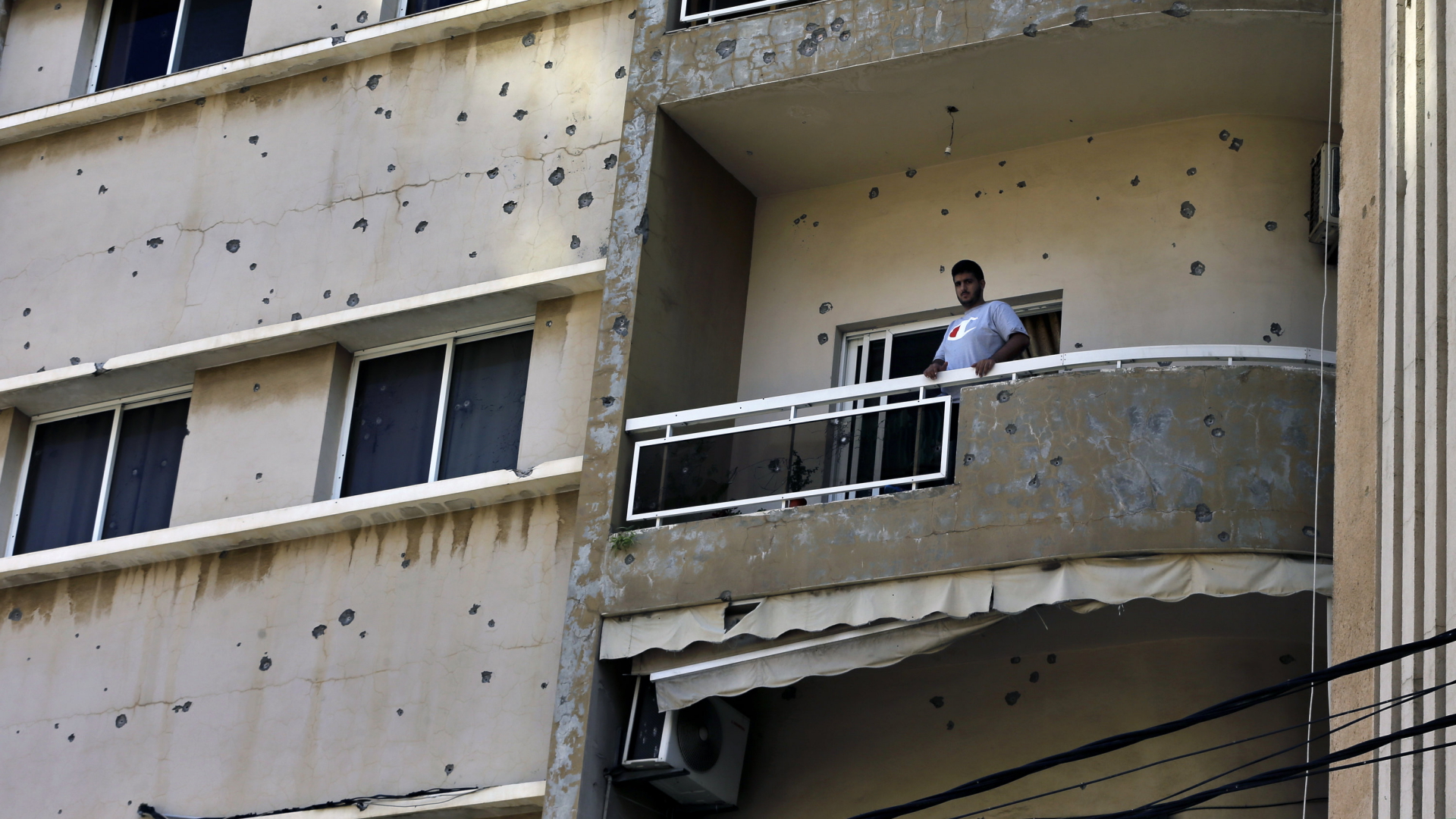 Ein Mann steht auf einem Balkon in einem von Einschlusslöchern betroffenen Haus | AP