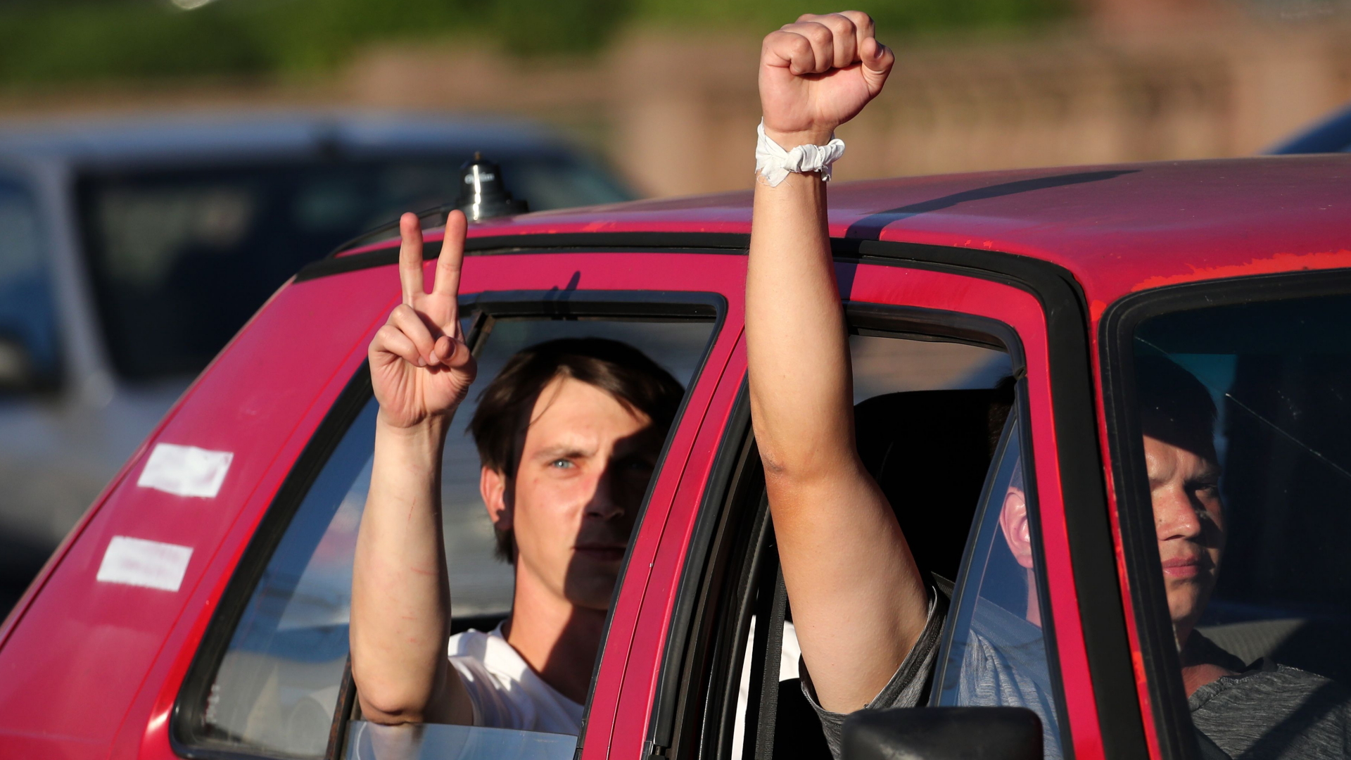 Insassen eines Autos zeigen Faust und Victory-Zeichen als Protest gegen Lukaschenko. | TATYANA ZENKOVICH/EPA-EFE/Shutte