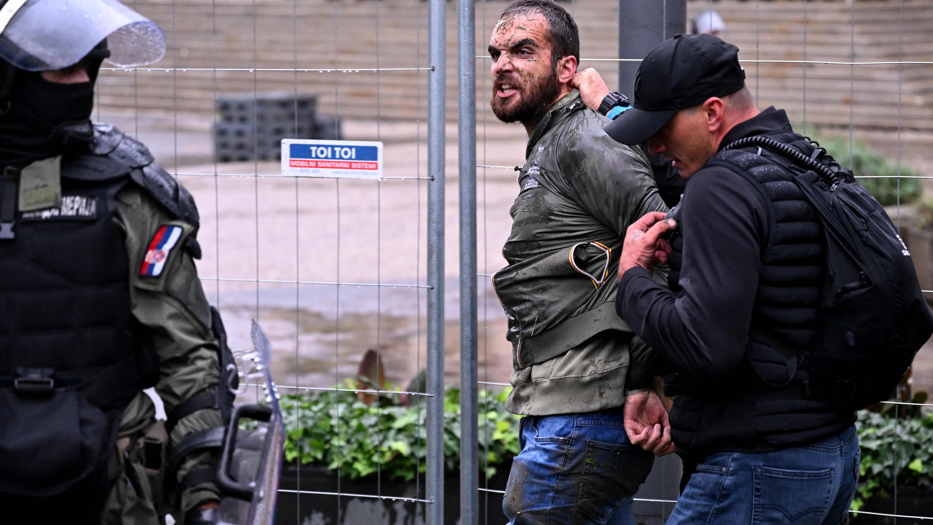 Ein Polizist führt einen festgenommenen Gegendemonstranten in Belgrad ab. | AFP