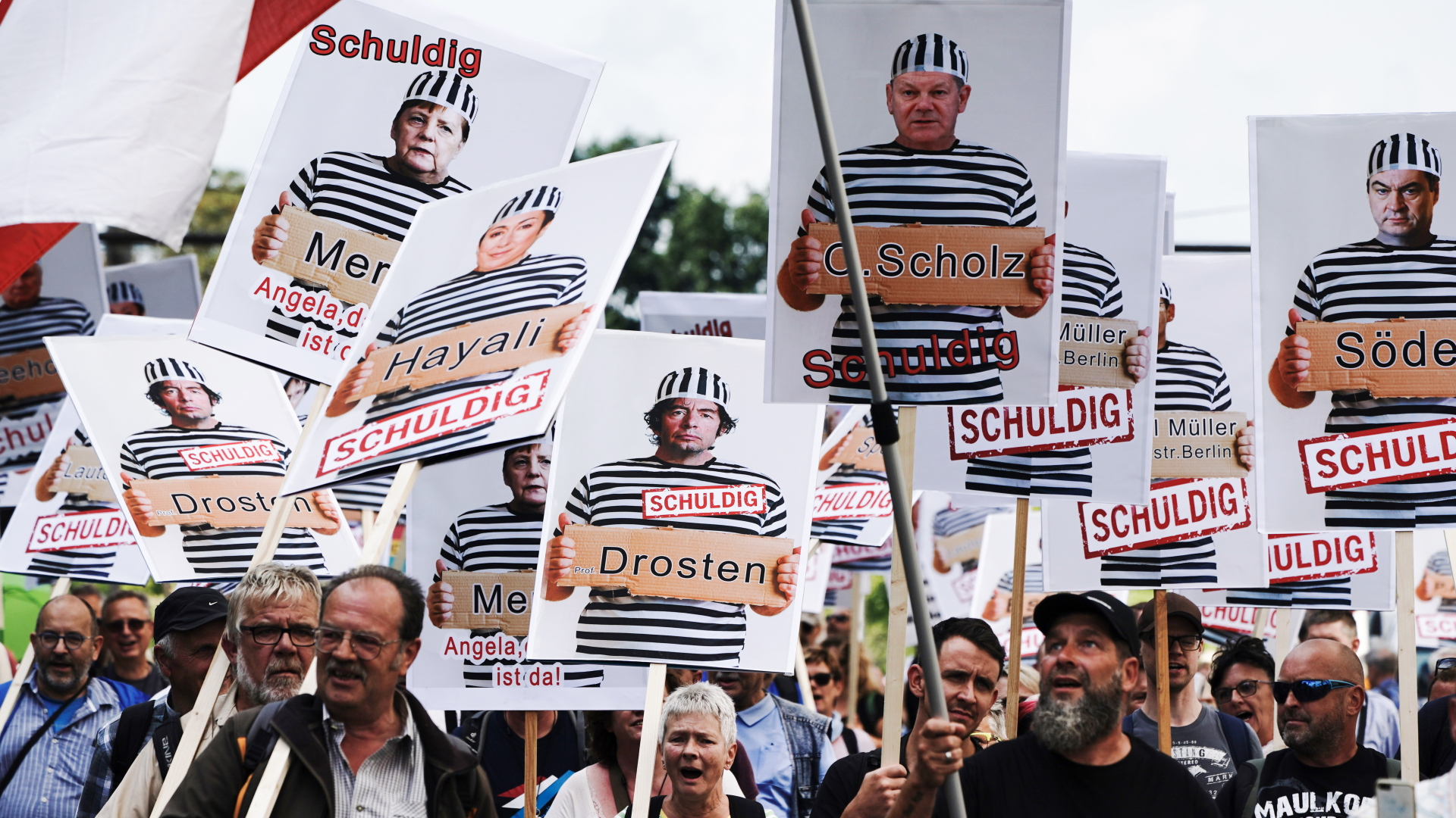 Auf Plakaten, die bei einer Anti-Corona-Demo in Berlin hochgehalten werden, sind Politiker und der Virologe Drosten abgedruckt. | dpa