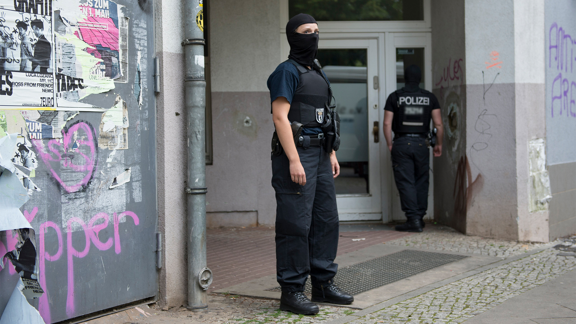 Vermummte Polizeibeamte stehen in Berlin vor einem Haus in Neukölln, in dem ein Mann nach dem spektakulären Diebstahl einer 100-Kilo-Goldmünze aus dem Berliner Bode-Museum festgenommen wurde (Bild vom 12.07.2018). | dpa