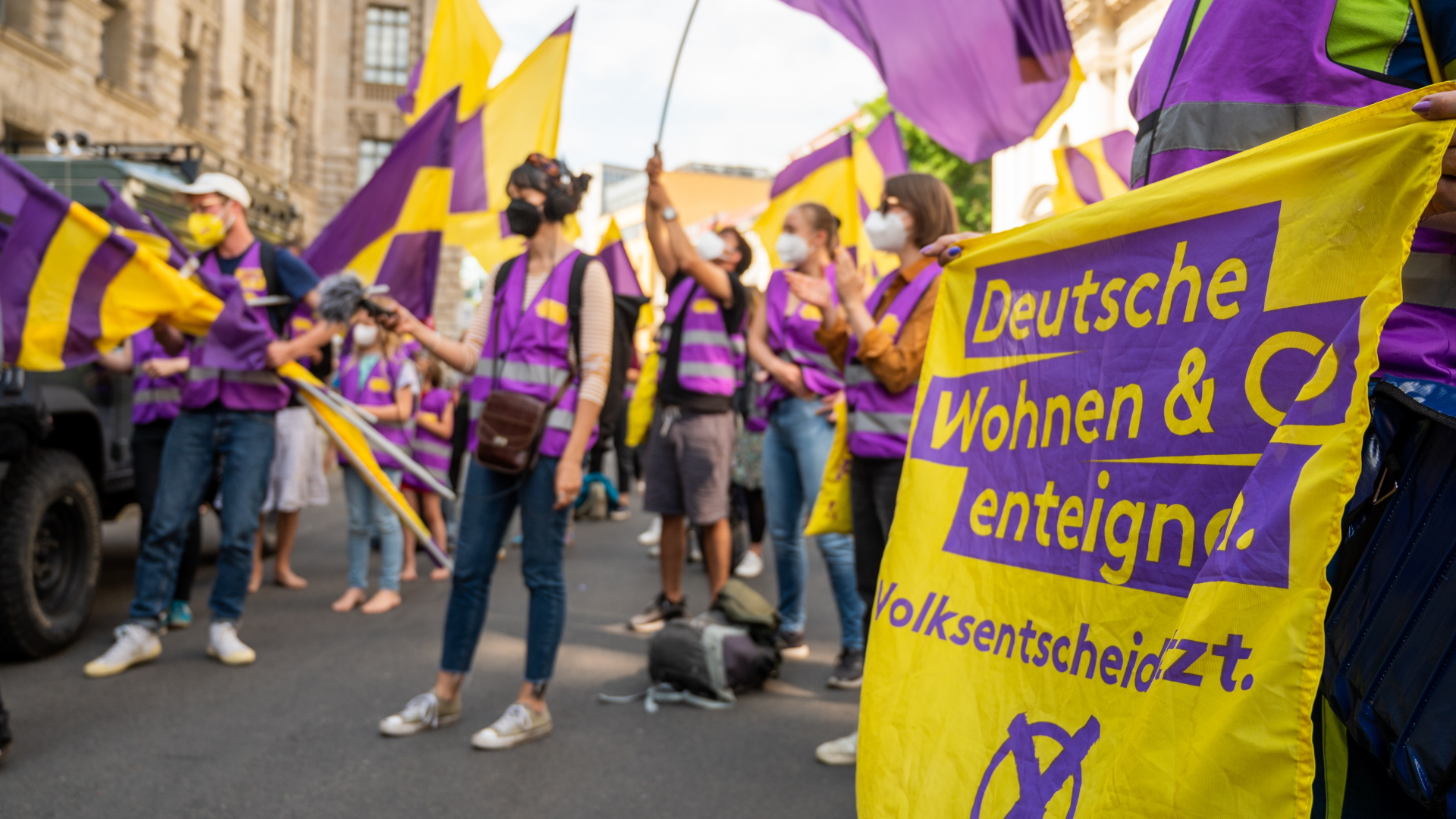 Unterstützer der Initiative "Deutsche Wohnen & Co. enteignen" schwenken ihre Fahnen bei der Übergabe der gesammelten Unterschriften für einen Volksentscheid zur Enteignung von großen Immobilienunternehmen. | dpa