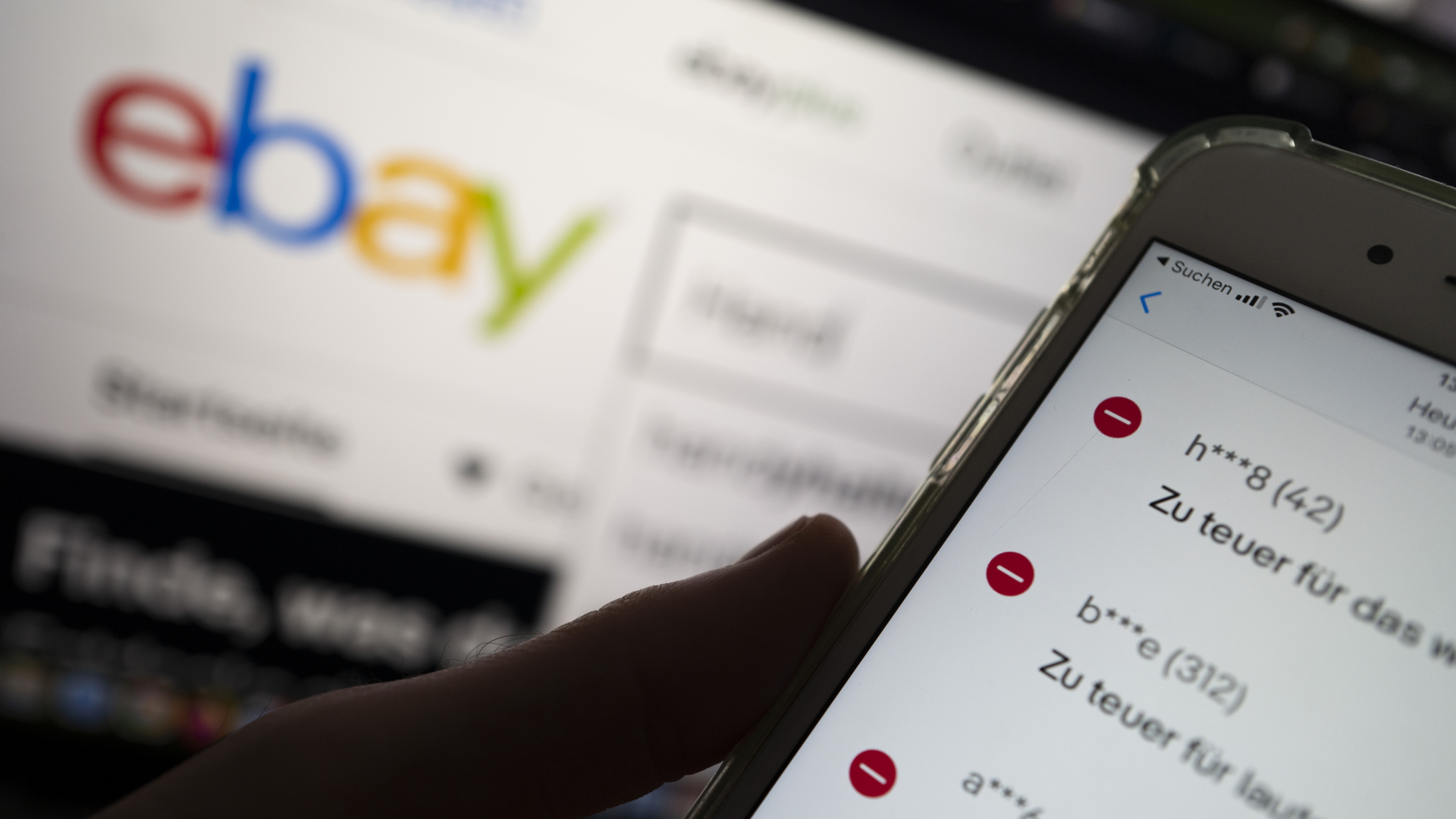 Auf einem Smartphone in der Ebay-App werden negative Bewertungen eines Verkäufers angezeigt, während im Hintergrund das Logo der Verkaufsplattform Ebay zu sehen ist.  | dpa