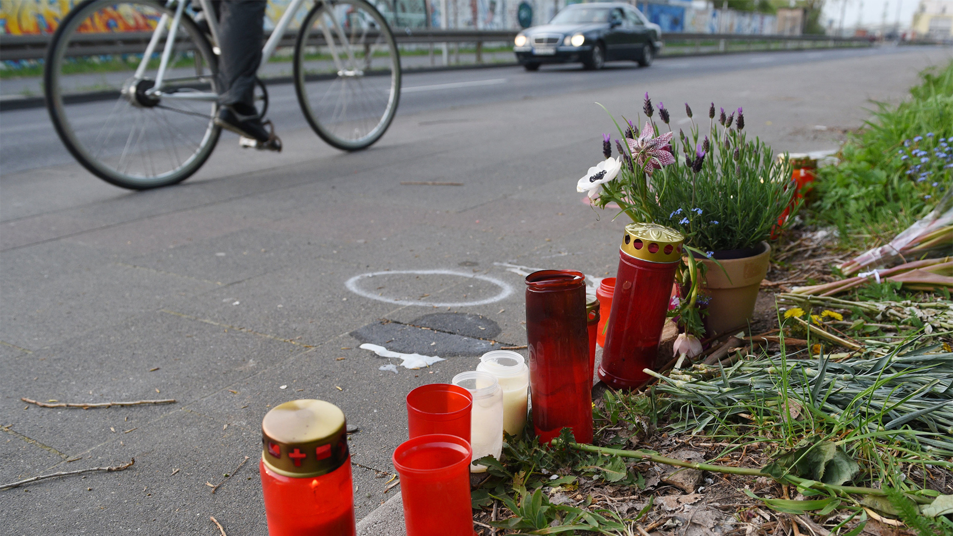 Grablichter und Blumen stehen in Köln an dem Unfallort
