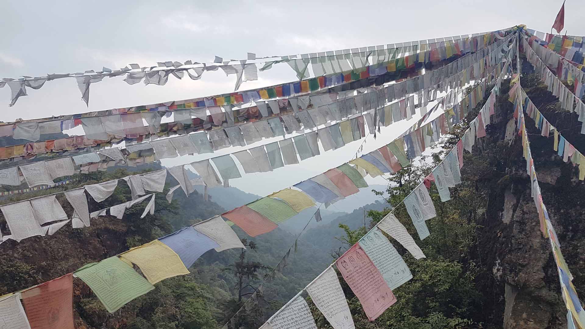 Buddhistische Gebetsfahnen hängen zwischen Felsen im zentral-bhutanesischen Phobjikha-Tal. | picture alliance/dpa