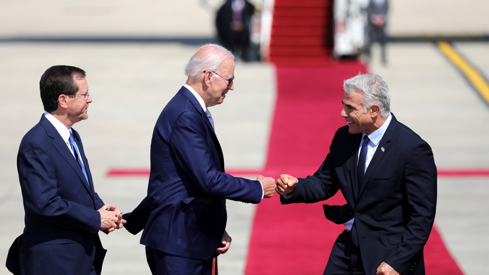 Joe Biden begrüßt in Israel Jair Lapid per Faust, links daneben steht Izchak Herzog. 