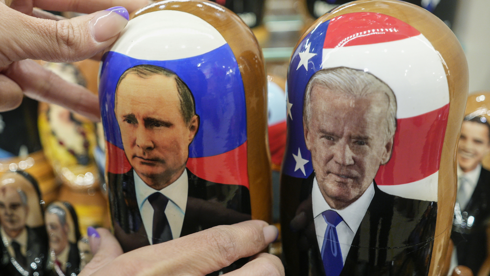 In einem Souvenirladen in Moskau (Russland) hält ein Kunde traditionelle Holzpuppen mit den Konterfeis von Biden und Putin in der Hand | dpa