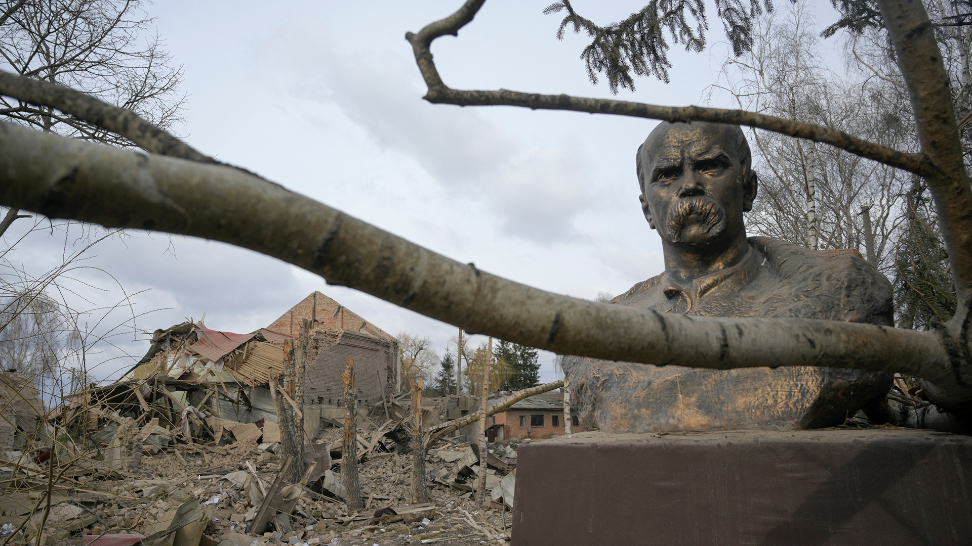 Vor einem zerstörten Haus steht die Büste eines bärtigen Mannes. | REUTERS