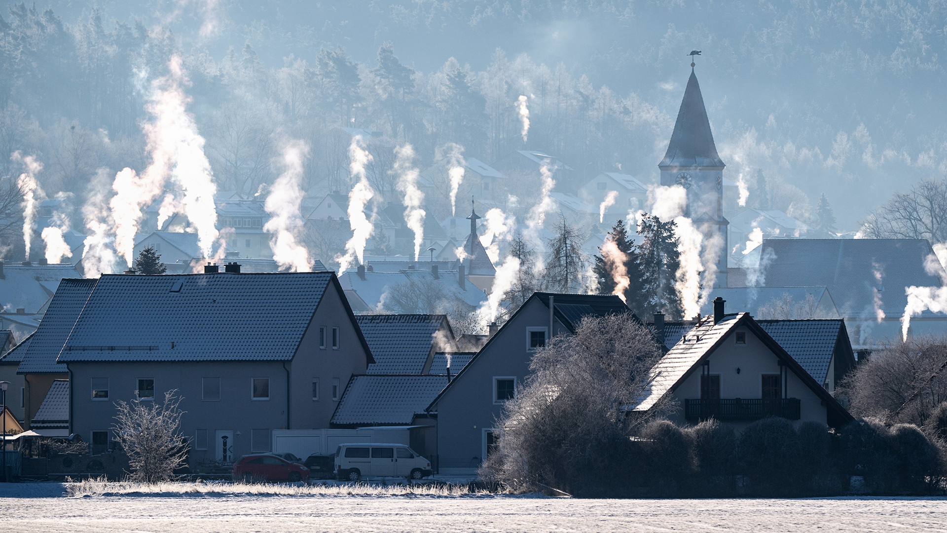 Die Schornsteine auf den Dächern der Häuser rauchen in der kalten Luft in Luthe-Wildenau/Bayern. | dpa