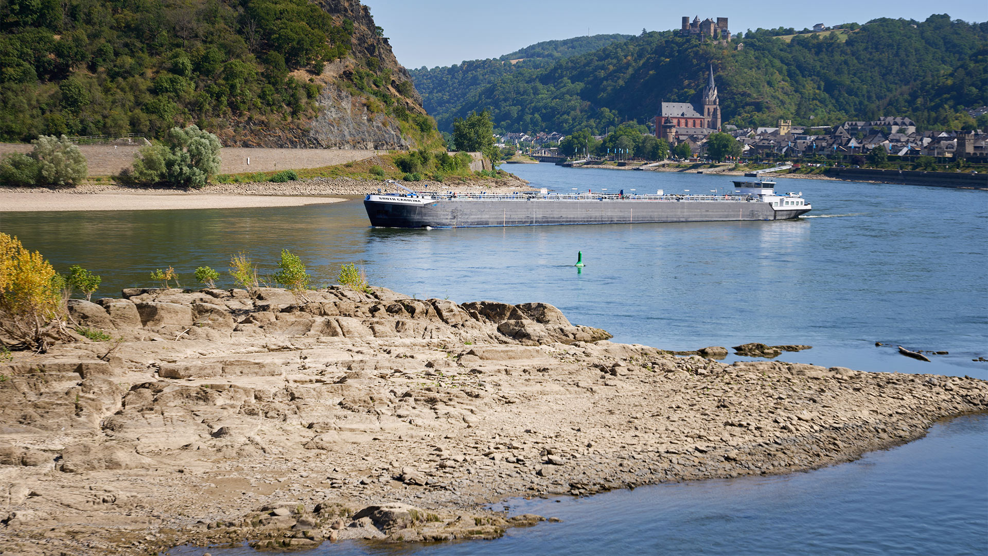 Ein Frachtschiff passiert auf dem Rhein einen Felsen. Durch die anhaltenden Trockenheit fällt der Wasserspiegel immer weiter. | picture alliance/dpa