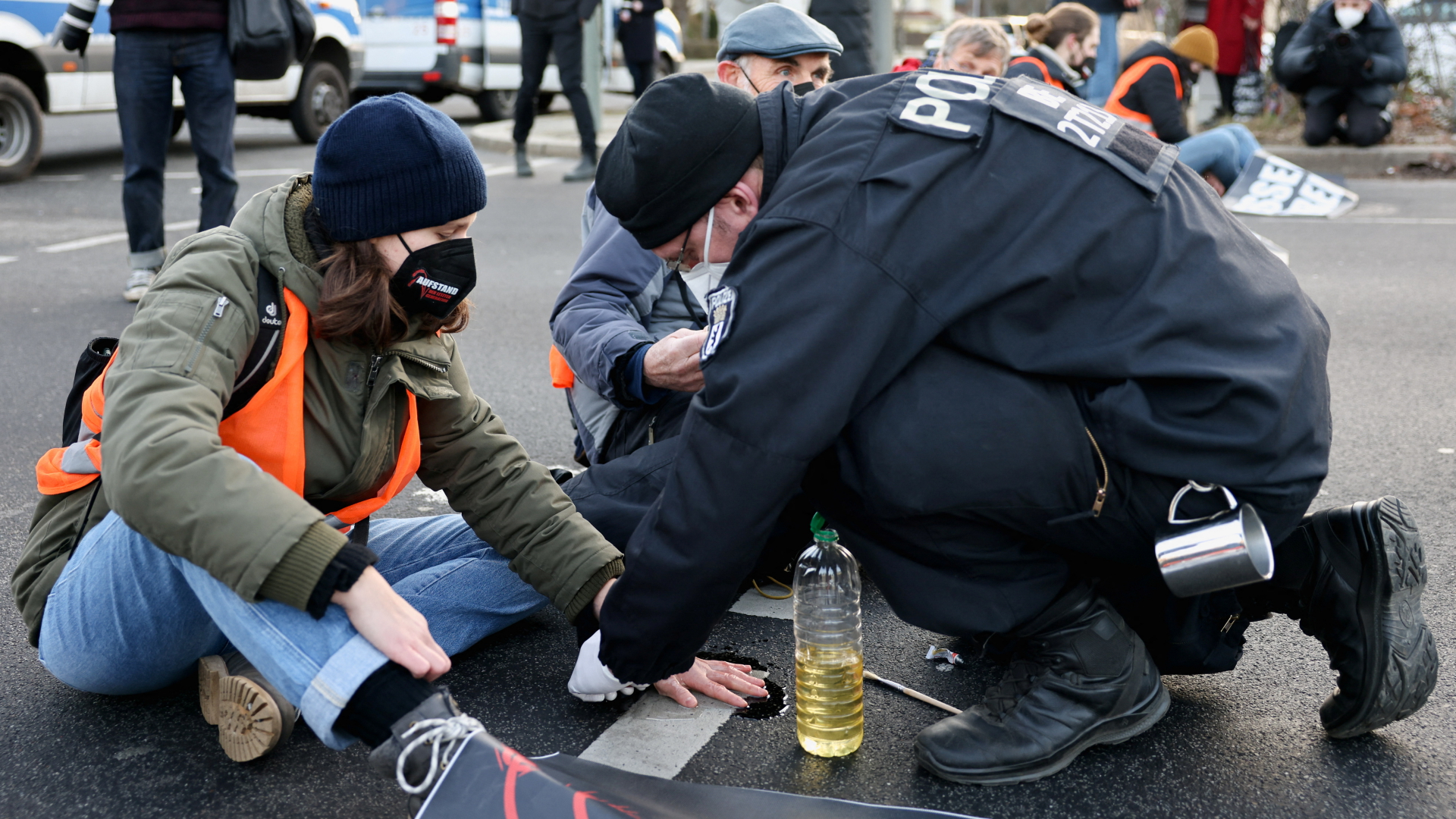 Ein Polizist löst die angeklebte Hand eines Klimaschutz-Aktivisten in Berlin von der Fahrbahn.