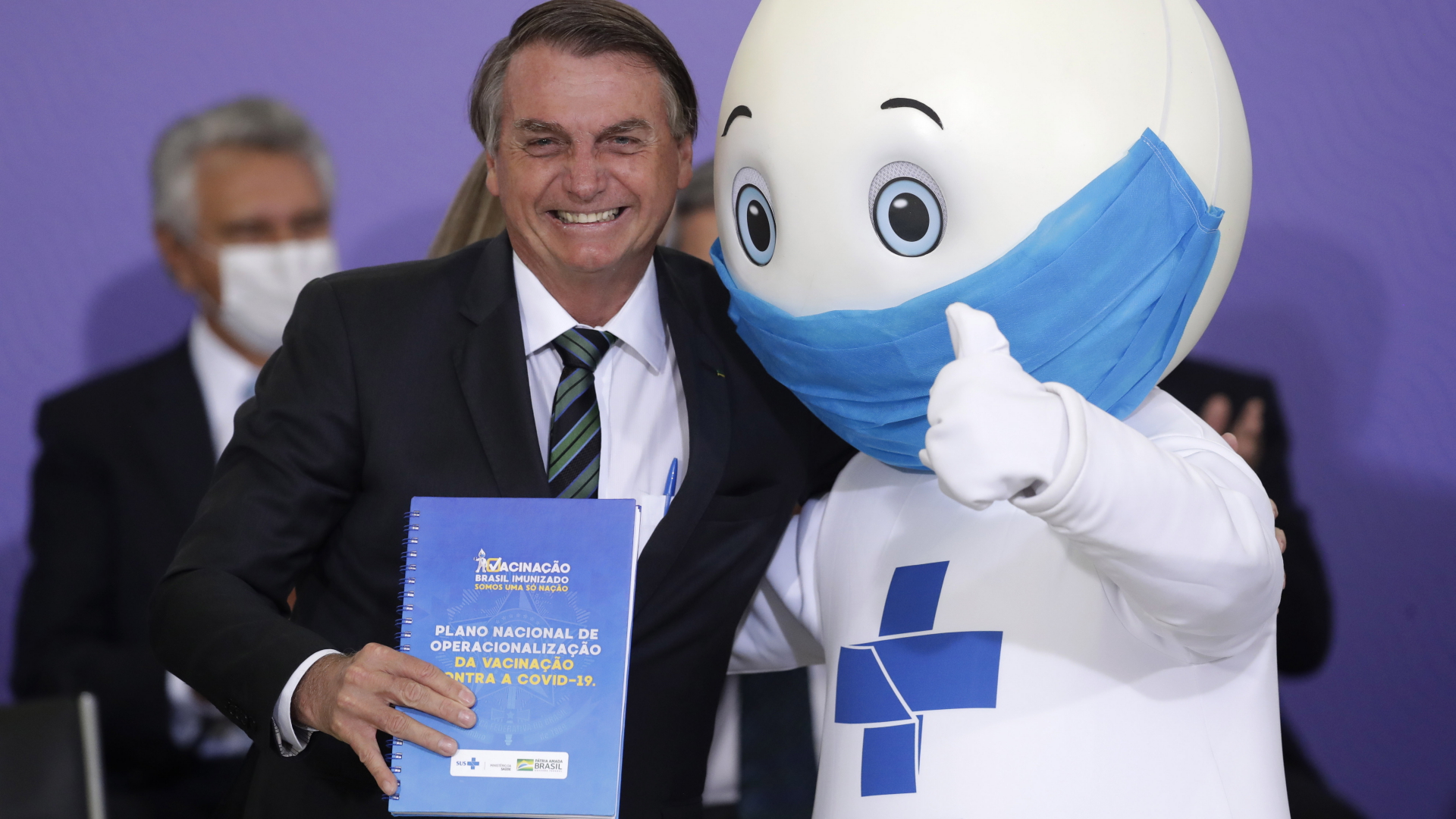 Jair Bolsonaro (l), Präsident von Brasilien, posiert für Fotos mit dem Maskottchen einer landesweiten Covid-Impfkampagne, genannt "Ze Gotinha". | dpa