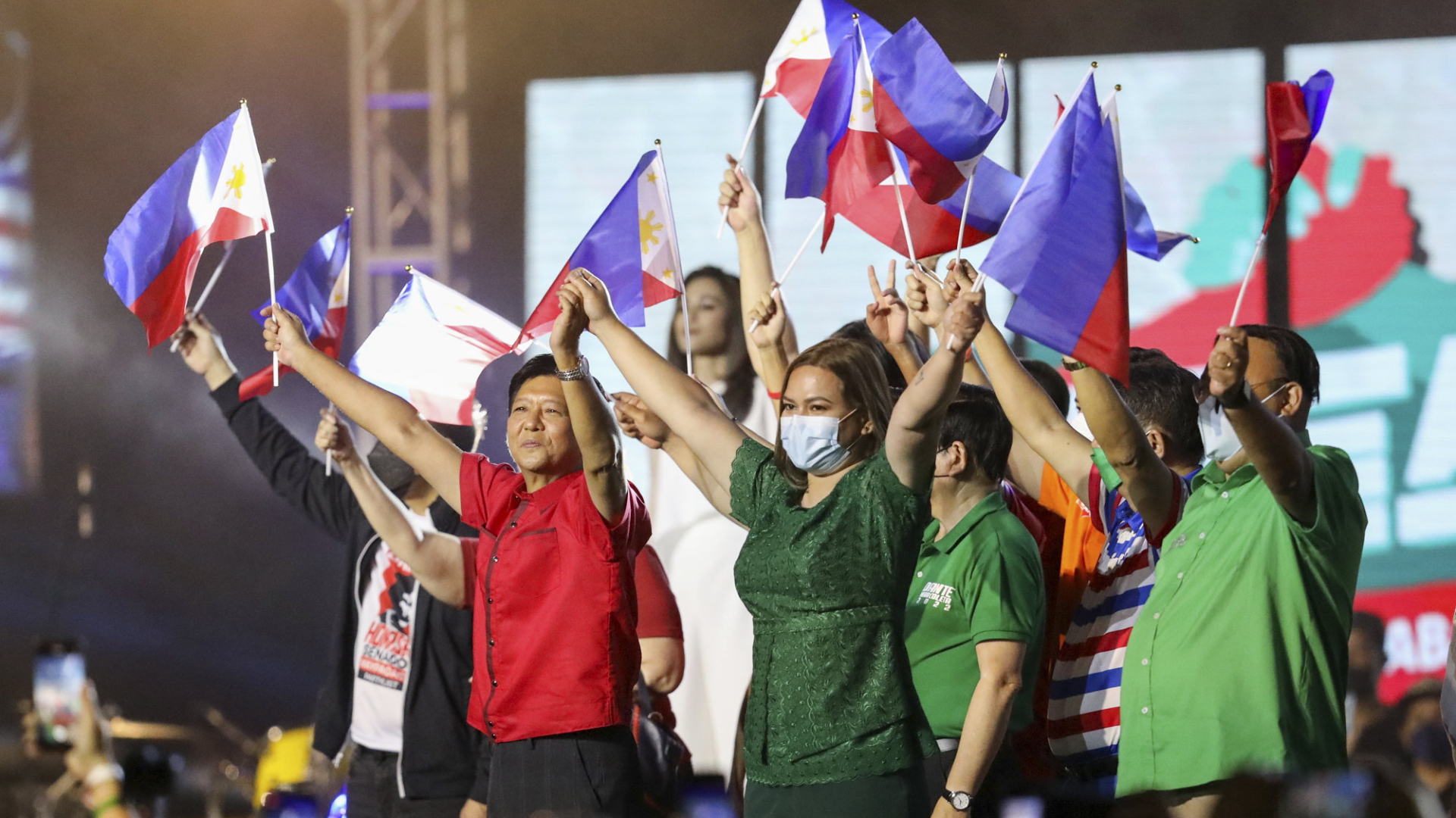 Ferdinand Marcos junior, genannt Bongbong, und Sara Duterte schwenken Nationalflaggen auf einer Bühne. | AP
