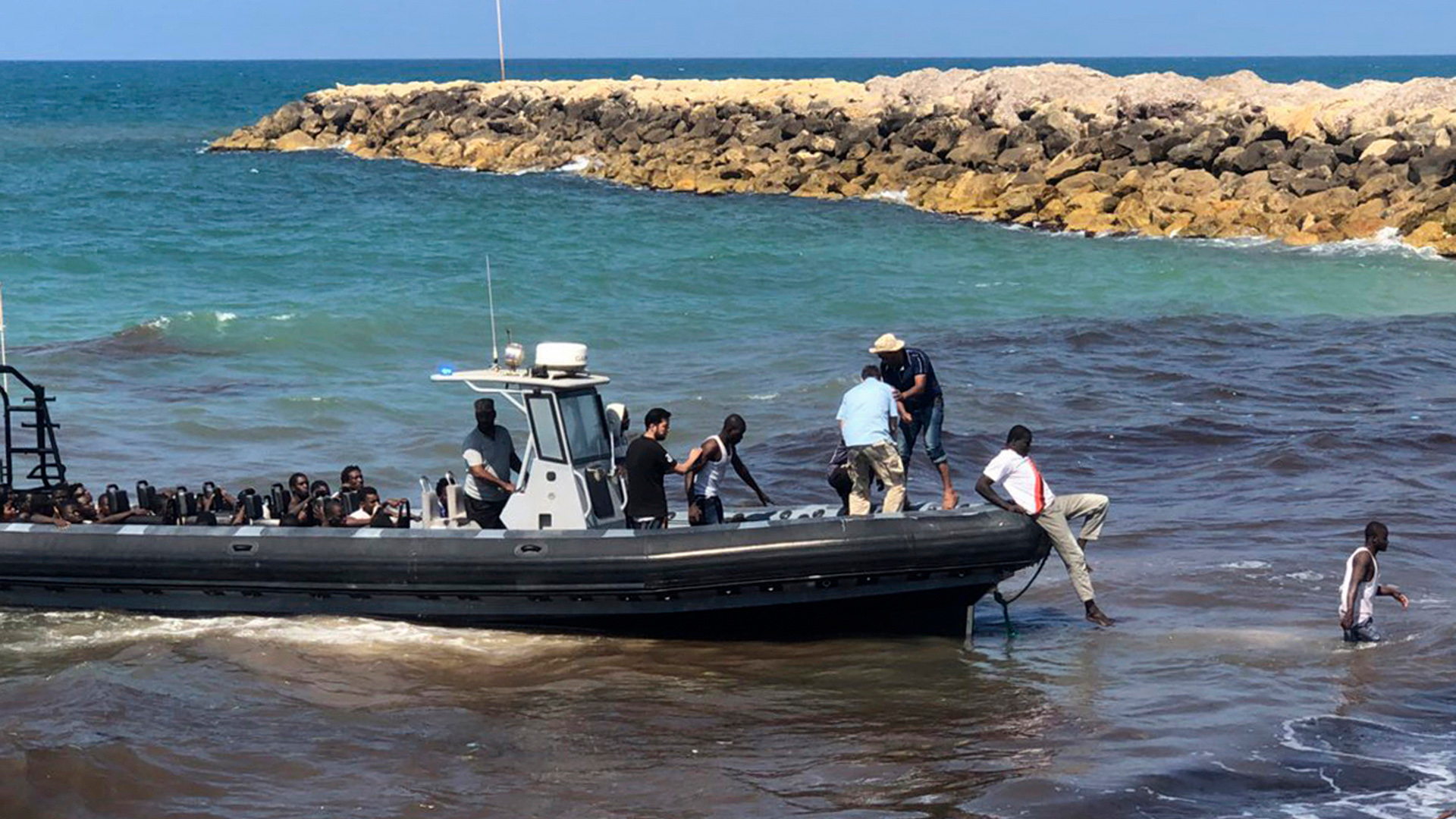 Dieses von der libyschen Küstenwache zur Verfügung gestellte Foto zeigt afrikanische Migranten, die im Osten der libyschen Hauptstadt in einem Boot an Land gebracht werden, Archivbild. | picture alliance/dpa