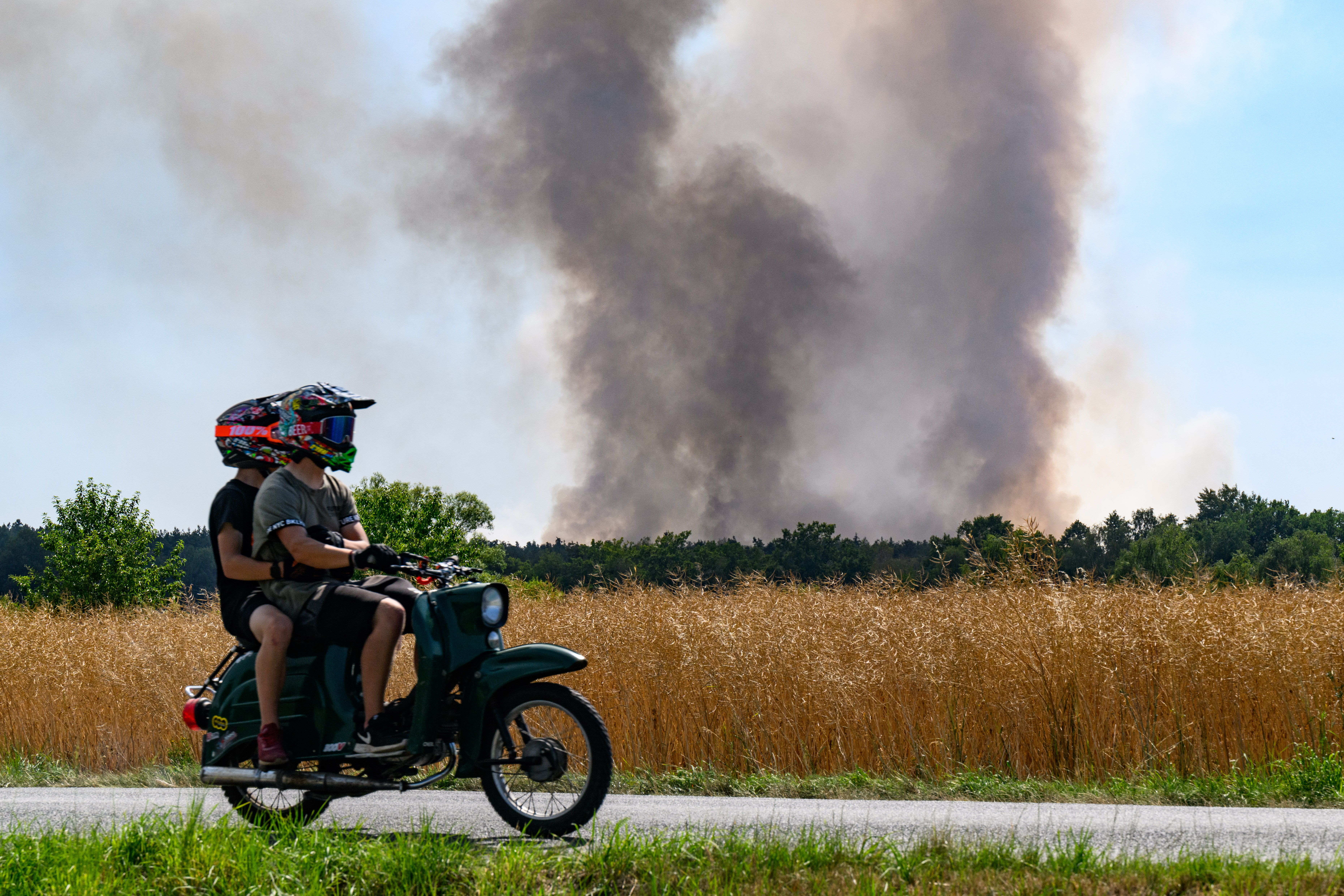 Ein Moped fährt vorbei an einer Rauchsäule in einem Wald der Königsbrücker Heide bei Radeburg, Sachsen. | dpa