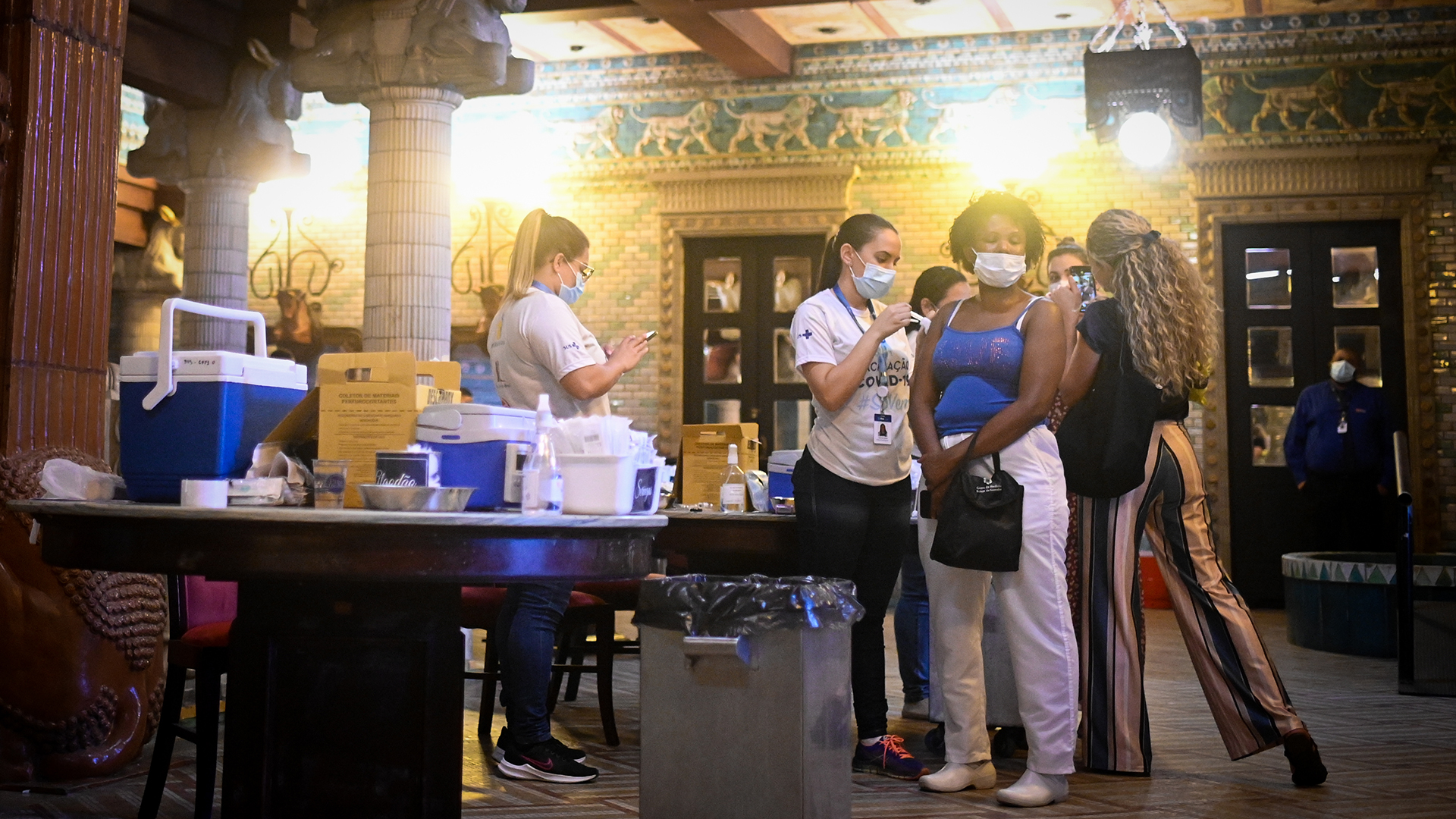 Ein Mitarbeiter des Gesundheitswesens verabreicht einer Frau im Stadttheater von Rio de Janeiro, in dem sich eine Impfstelle  befindet, eine Dosis des Impfstoffs gegen Covid-19. | dpa