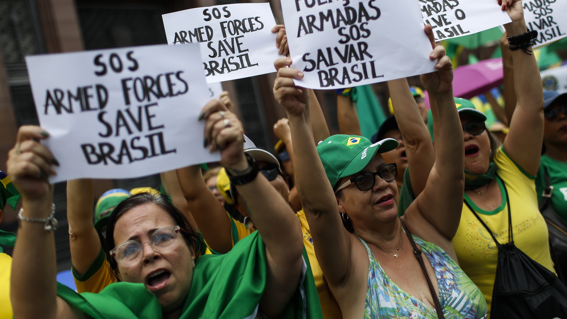 "SOS Armed Forces Save Brasil" (SOS Streitkräfte, rettet Brasilien), steht auf den Plakaten, die eine Gruppe Frauen bei einem Protest vor einer Militärbasis hoch heben. | dpa