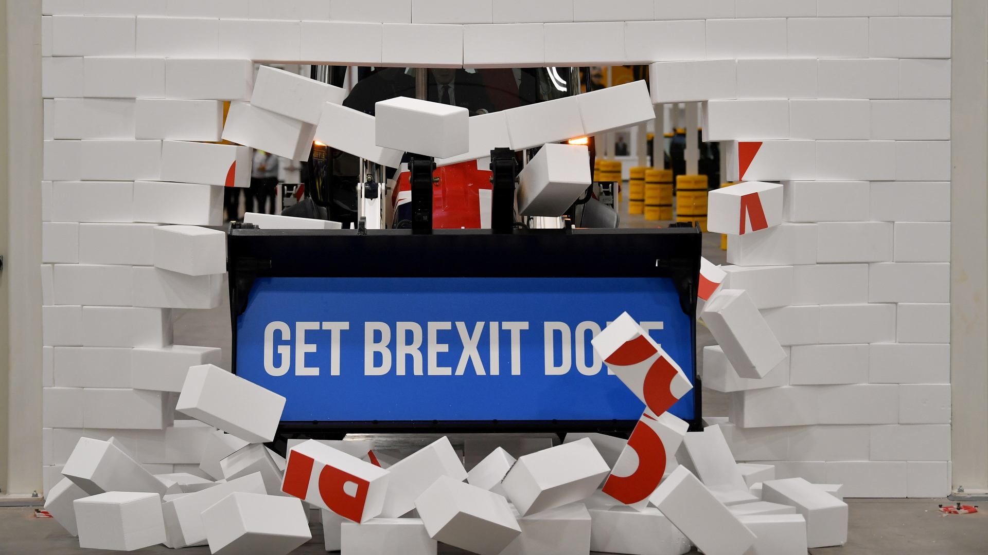 Eine Baggerschaufel mit dem Slogan "Get Brexit Done" durchbricht eine weiße Wand. | REUTERS