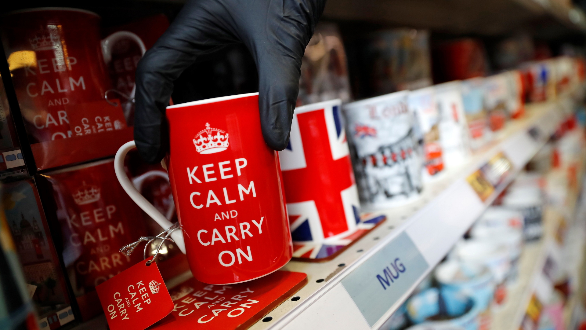 Jemand stellt eine rote Tasse mit der Aufschrift "Keep calm and carry on" in ein Regal. | AFP