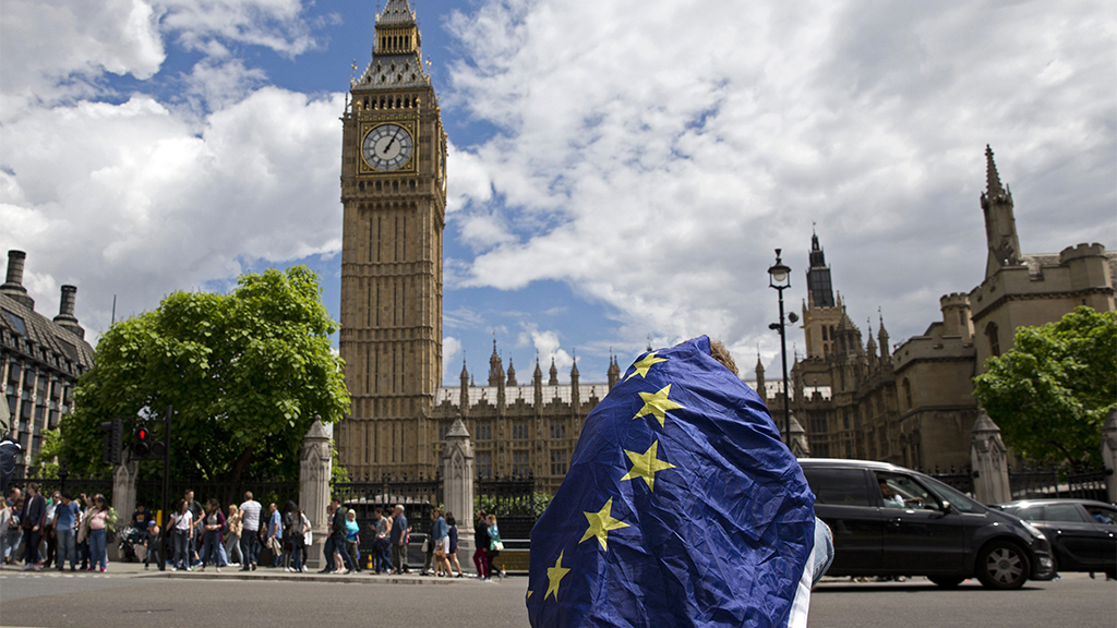 Ein Mann sitzt eingewickelt in eine EU-Flagge vor dem Parlamentsgebäude in London