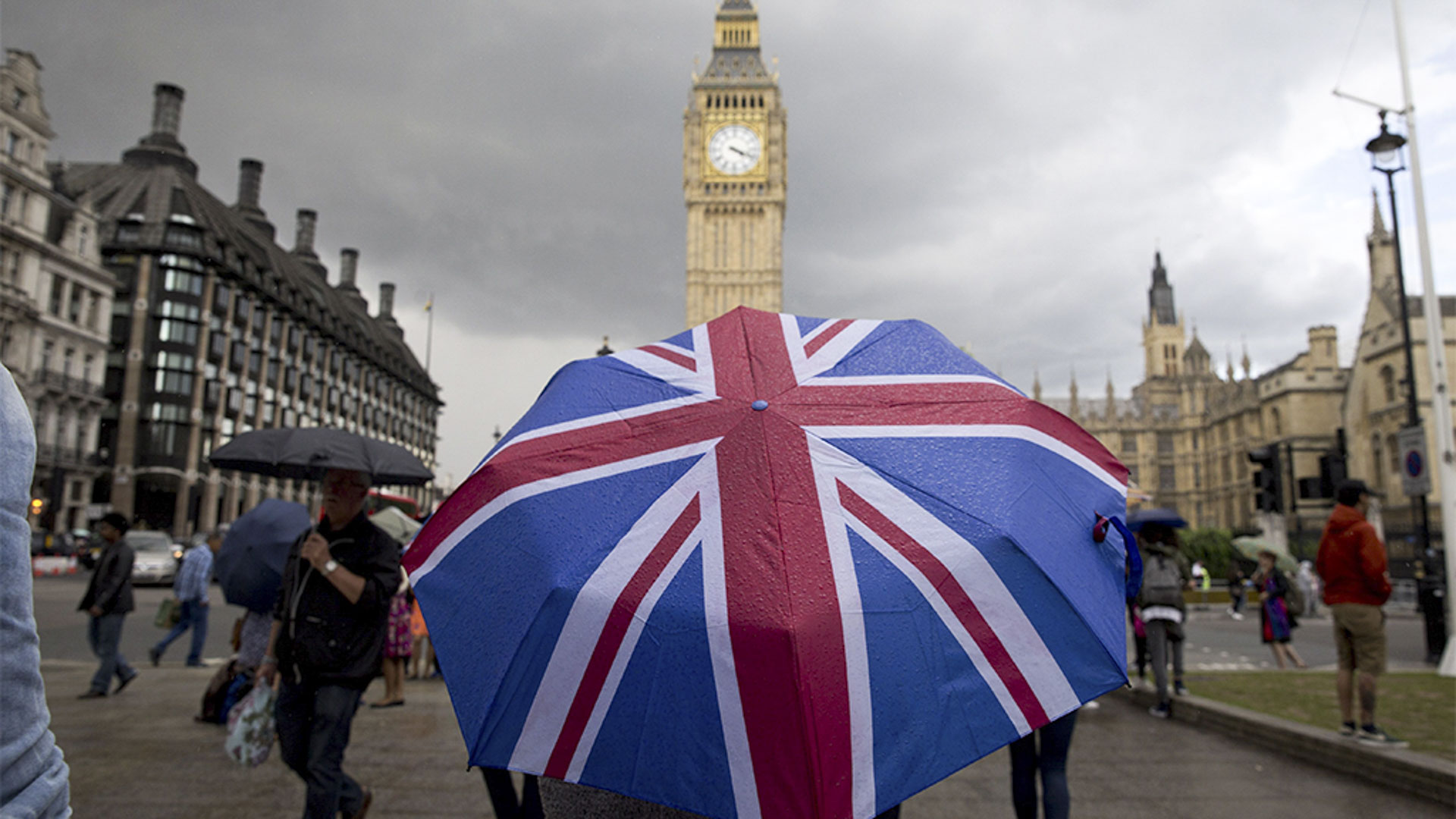 Ein aufgespannter Regenschirm mit dem Muster der Flagge Großbritanniens vor dem Parlamentsgebäude in London