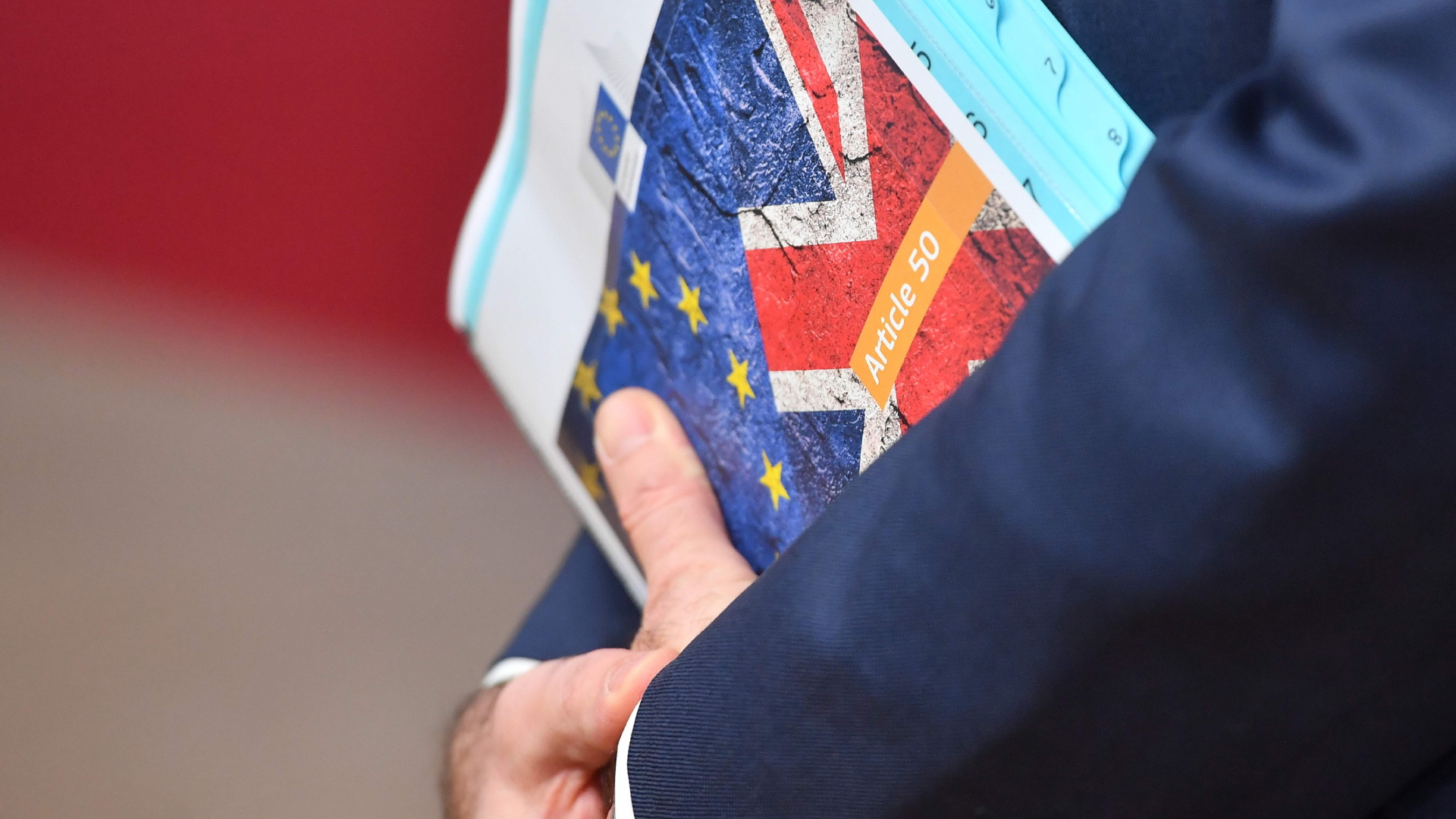 Flaggen der EU und Großbritanniens auf Aktenordnern, die ein Mann in der Hand hält