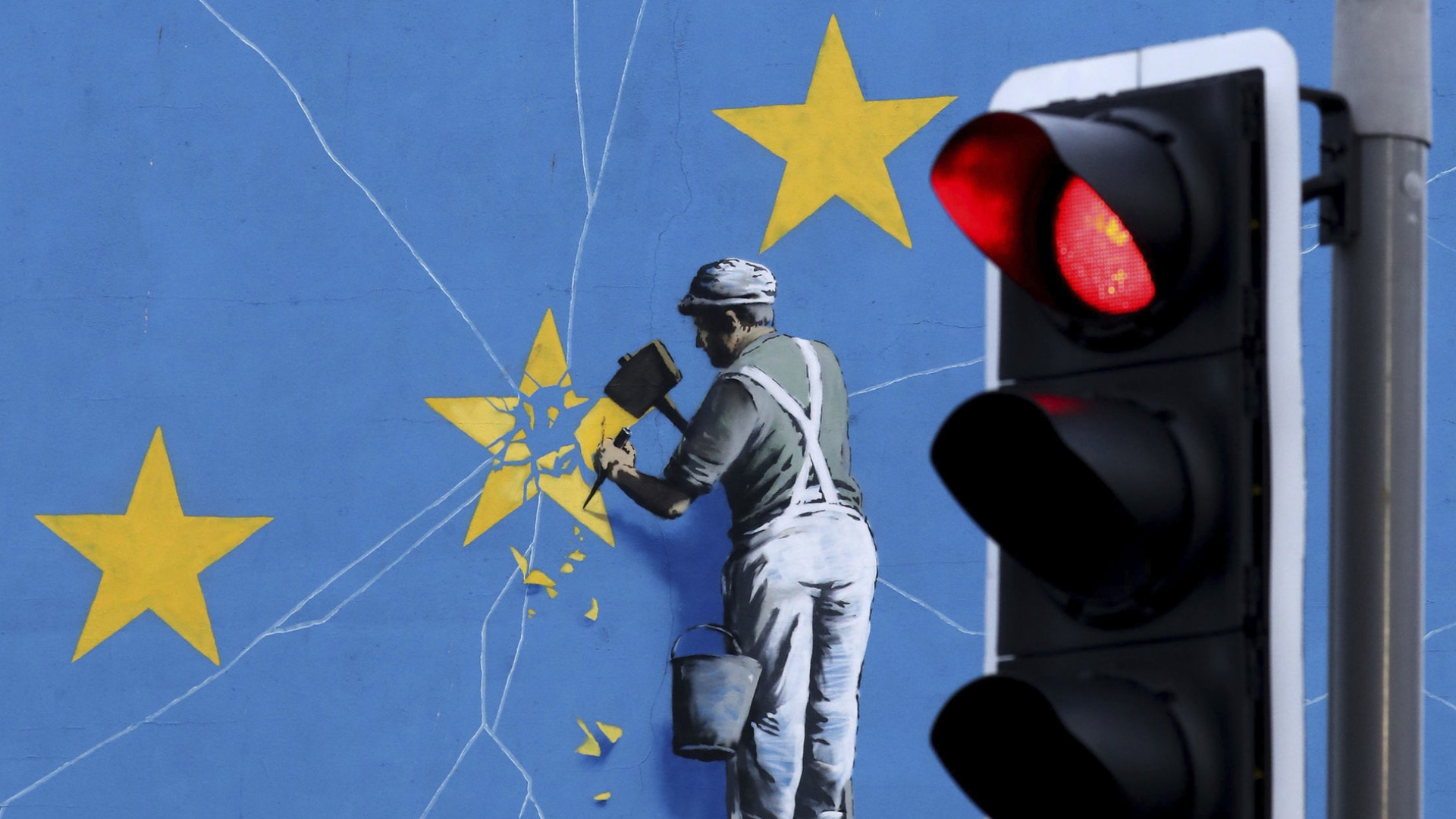 Das Brexit-Wandbild des Künstlers Banksy zeigt einen Mann, der einen Stern aus dem EU-Wappen heraushämmert. | AP