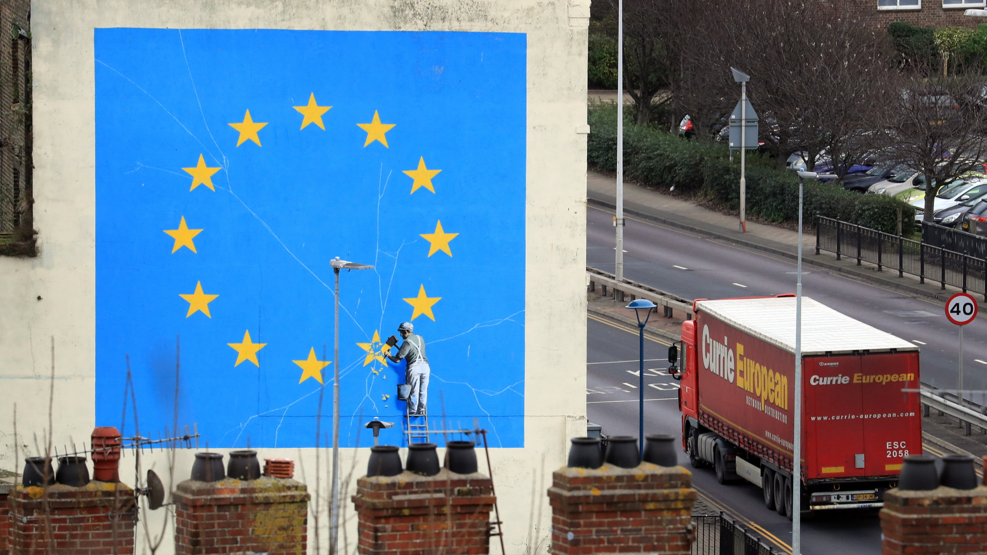 Ein Lastwagen, der zum Hafen von Dover in Kent fährt, passiert ein Wandbild des Künstlers Banksy. | dpa