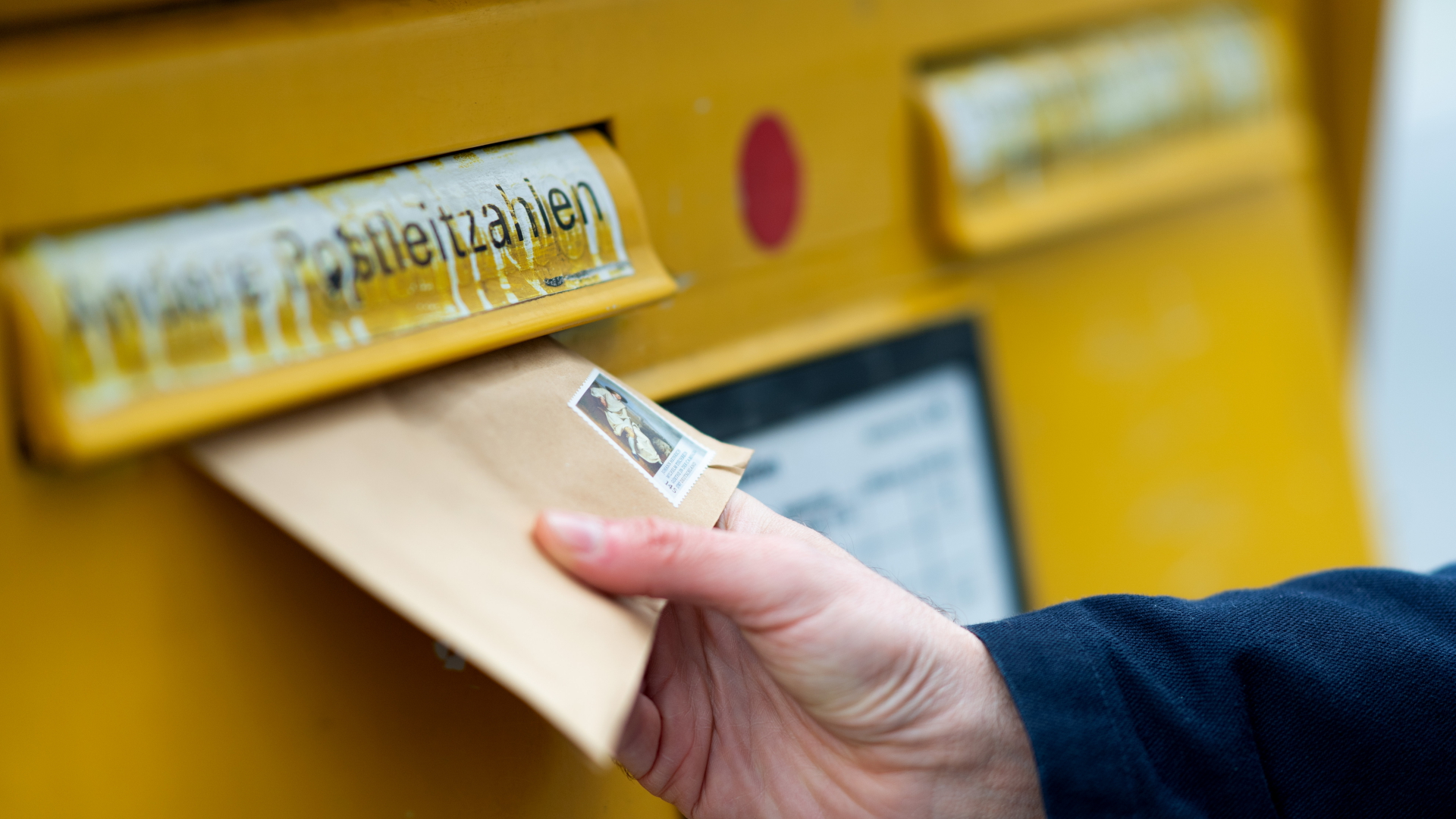 Hand wirft einen Brief in einen Briefkasten der Deutschen Post | dpa
