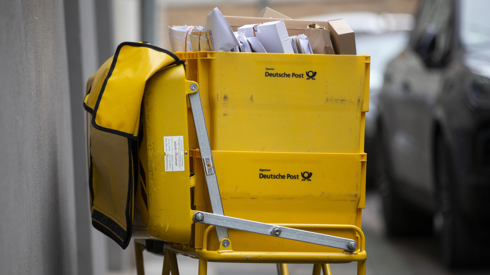 Ein Briefträgerwagen der Deutschen Post steht auf einer Straße
