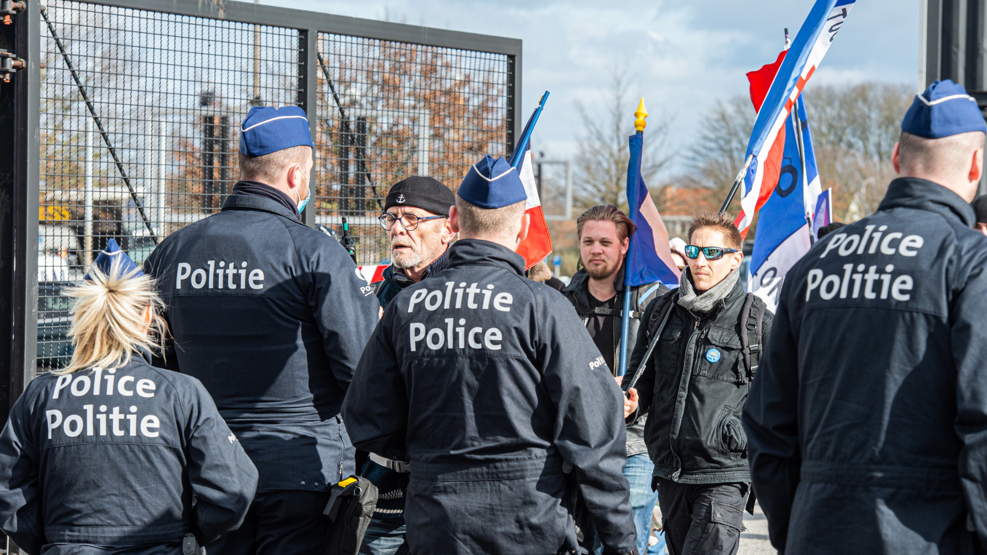 Polizisten stehen vor Protestierenden gegen die Corona-Maßnahmen der Regierung auf dem Parkplatz außerhalb von Brüssel in Belgien. | dpa