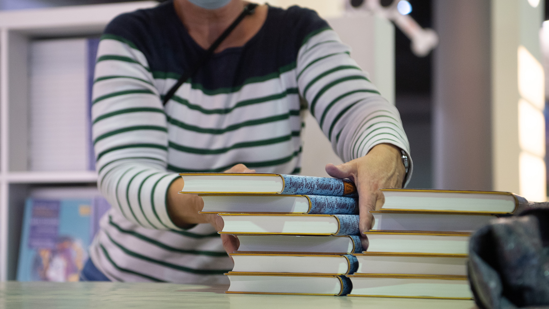 Eine Frau stapelt Bücher an einem Stand der Frankfurter Buchmesse. | dpa