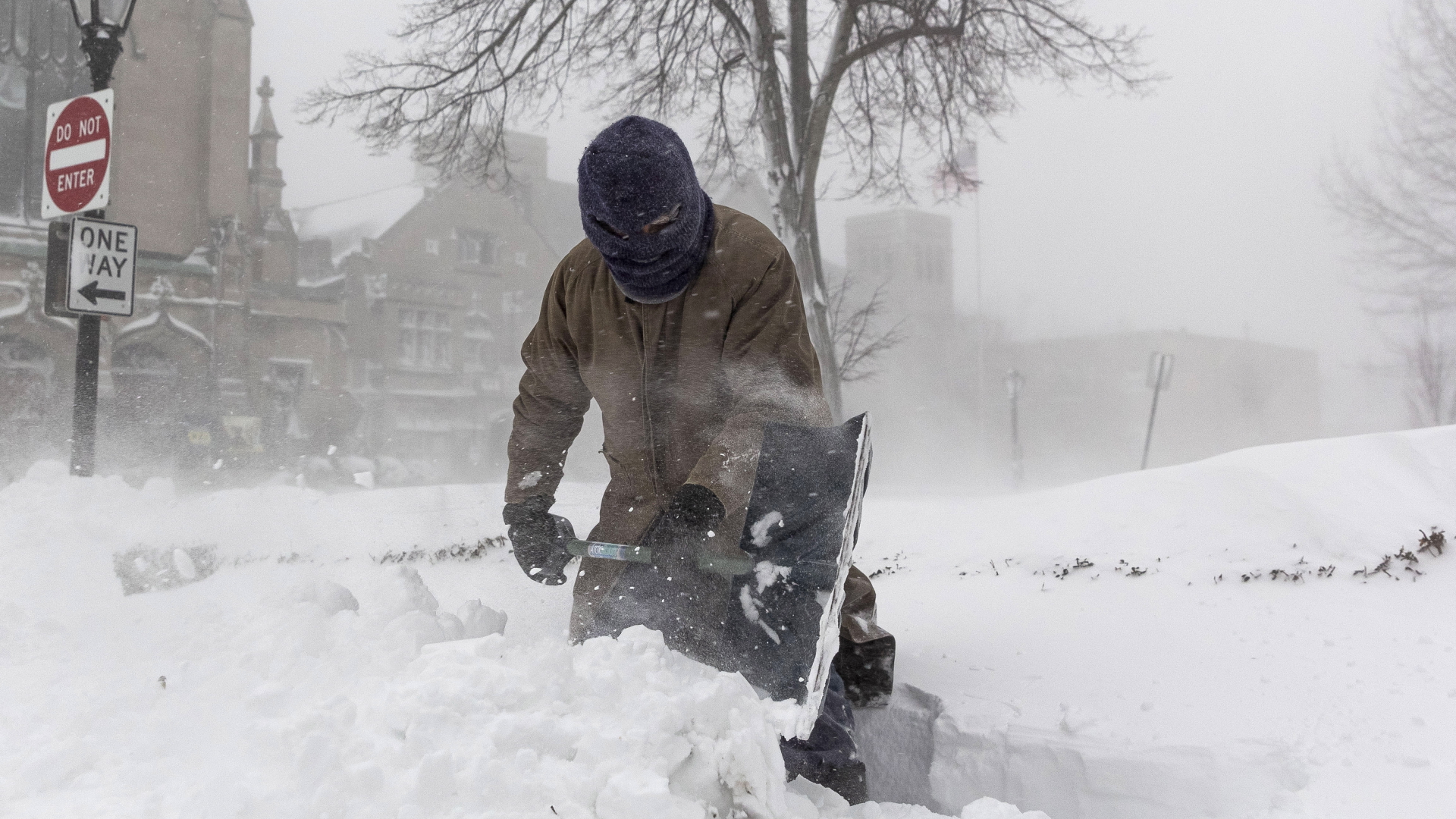 Ein vollständig vermummter Mensch schaufelt Schnee im Buffalo. | EPA