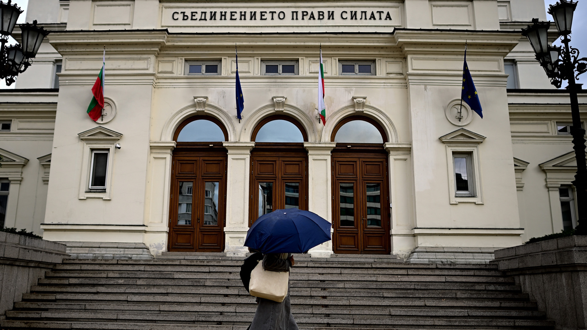 Eine Passantin mit Regenschirm geht vor dem bulgarischen Parlamentsgebäude in Sofia entlang.