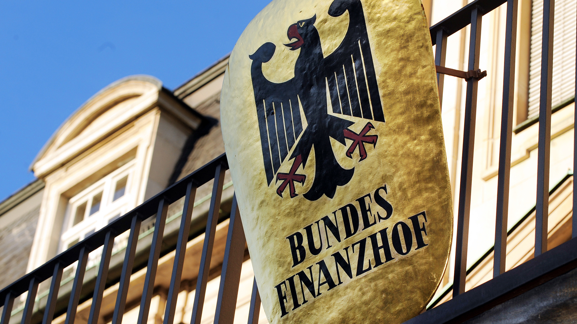 Ein Schild mit der Aufschrift "Bundesfinanzhof" hängt vor dem Bundesfinanzhof (BFH) an einem Zaun.