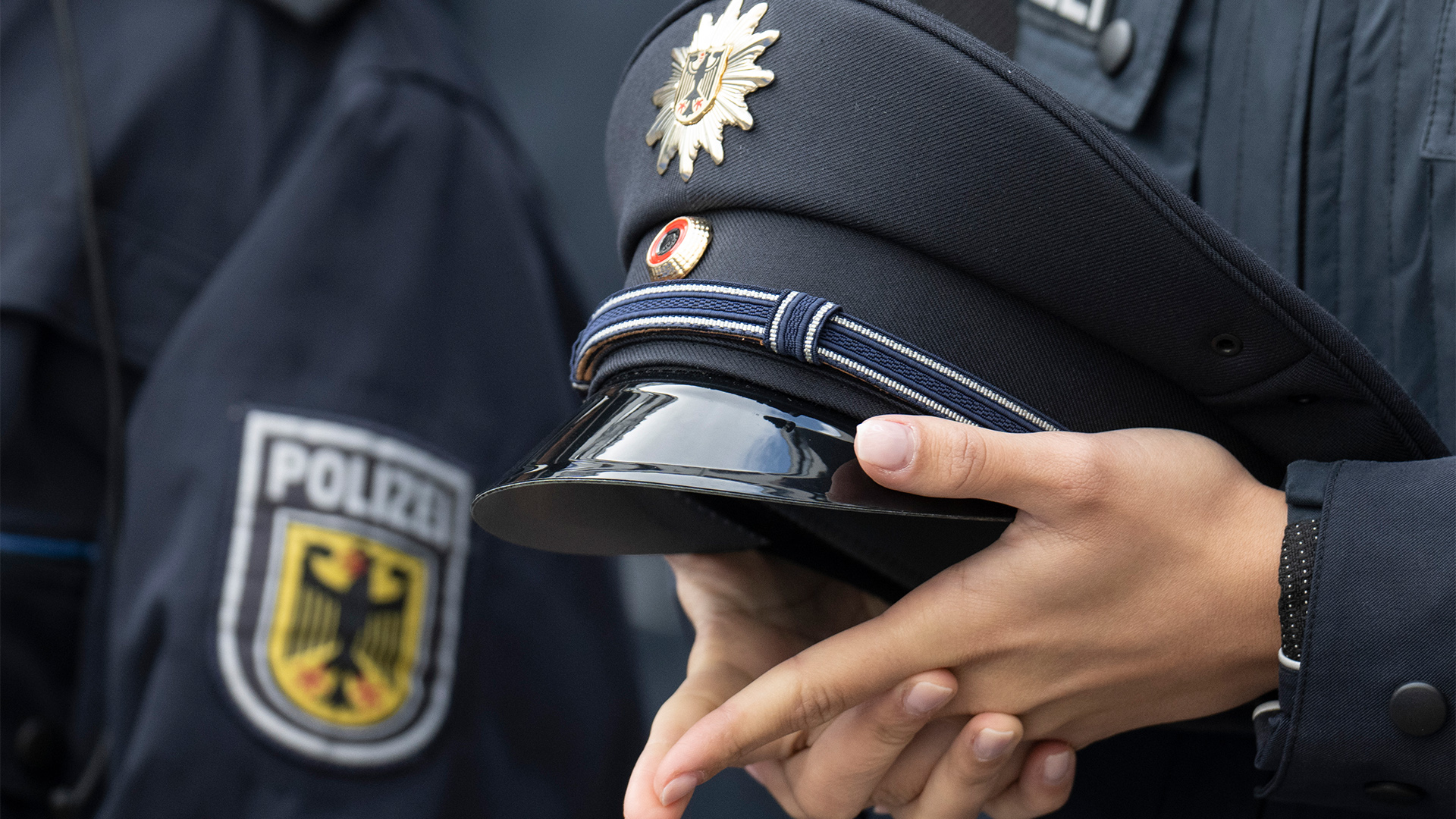  Eine junge Bundespolizistin hält ihre Mütze in den Händen.  | picture alliance/dpa
