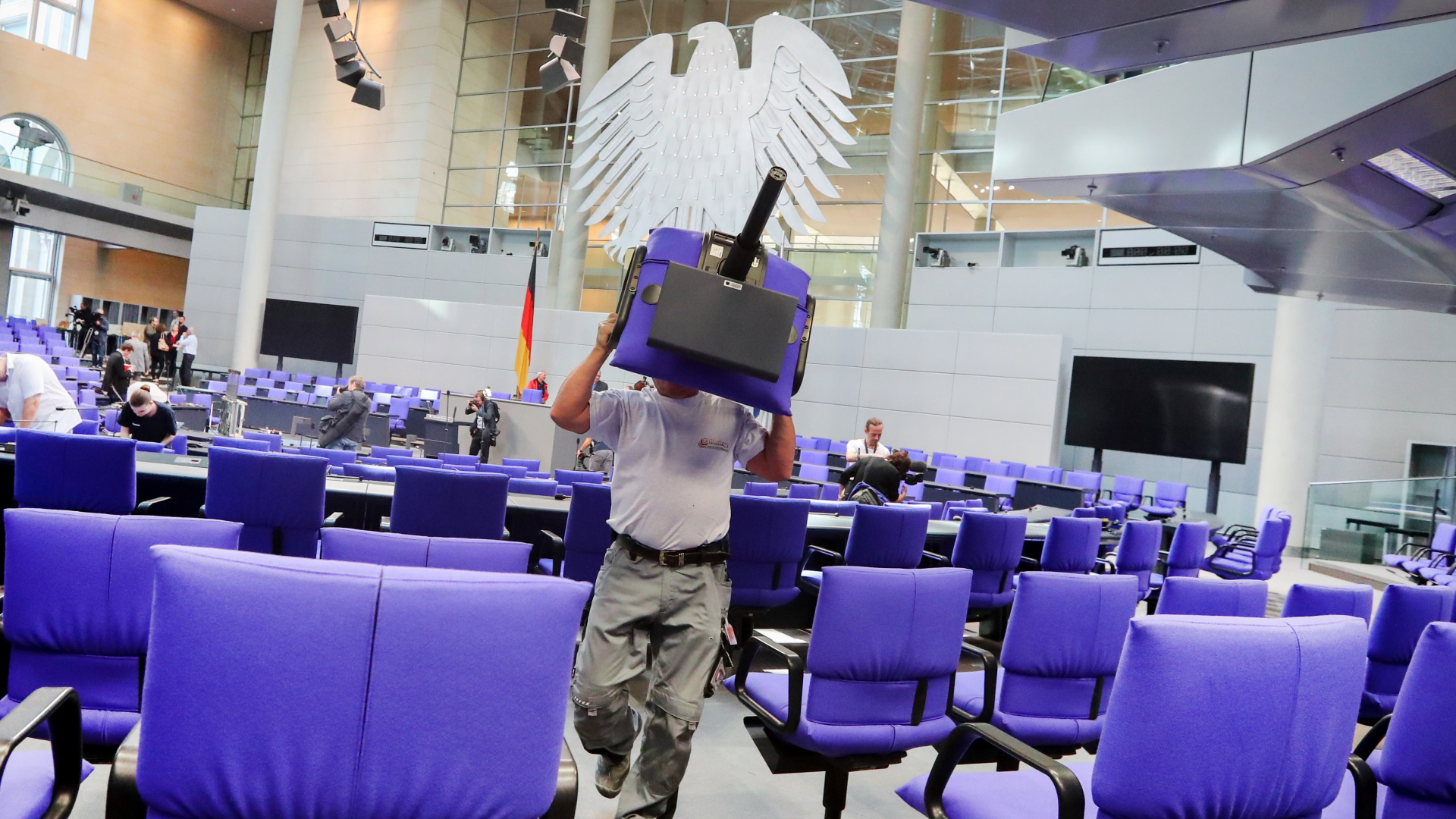 Ein Arbeiter trägt Stühle im Bundestag (Archivbild) | dpa